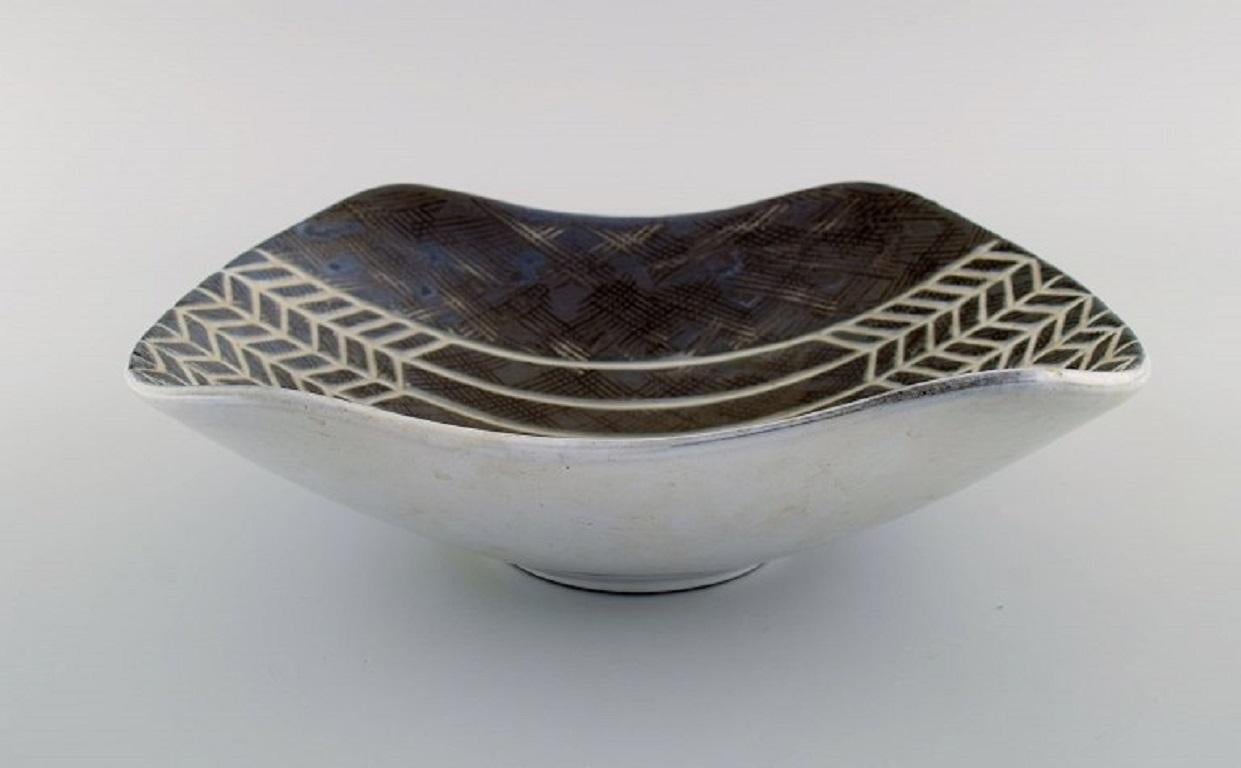 Mari Simmulson (1911-2000) for Upsala-Ekeby. Large bowl in glazed stoneware from her well-known Ax series. Incised grain decor on brown background. 
Mid-20th century.
Measures: 29.5 x 20 x 9 cm.
In excellent condition.
Stamped.