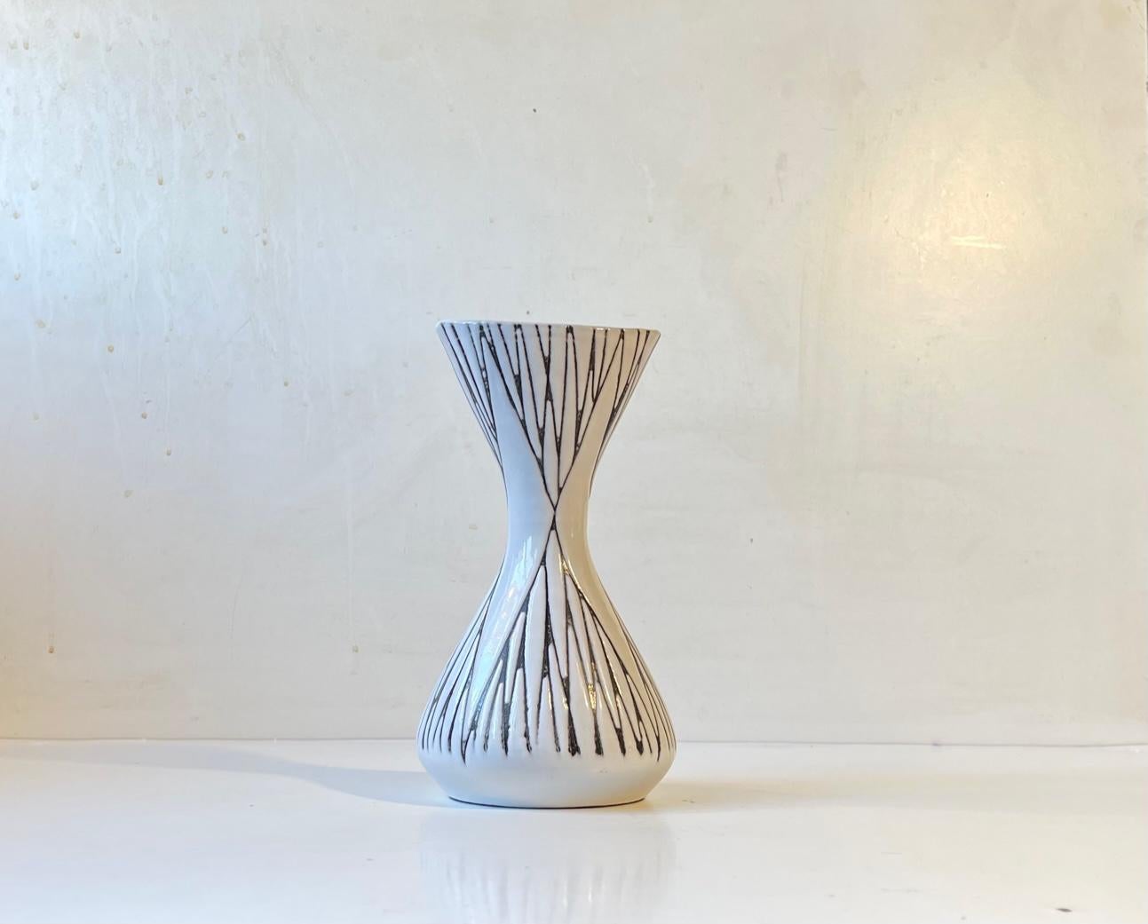 A rare hour-glass - diablo shaped vase by female ceramist Mari Simmulson.. It is called Mars and features incised lines creating a pointy geometric pattern bursting through its white main-glaze. Made Ca. 1960 at Upsala Ekeby in Sweden. Fully