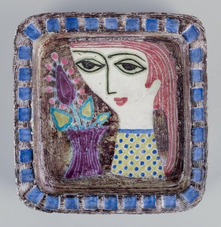 Mari Simmulson (1911-2000) for Upsala Ekeby.
Ceramic dish featuring a woman and flowers in a vase motif.
Polychrome glaze.
From around the 1960s.
Model 4156.
Marked.
In perfect condition.
Dimensions: 18.0 cm x 17.5 cm x Height 4.0 cm.

Mari