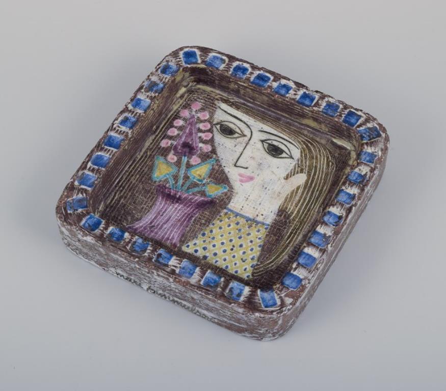 Mari Simmulson (1911-2000) für Upsala Ekeby. Keramiktablett mit dem Motiv einer Frau und Blumen in einer Vase. Polychrome Glasur.
Etwa ab den 1960er Jahren.
Modell 4156.
Markiert.
In perfektem Zustand.
Abmessungen: 18,0 cm x 18,5 cm x 4,0 cm.

Mari