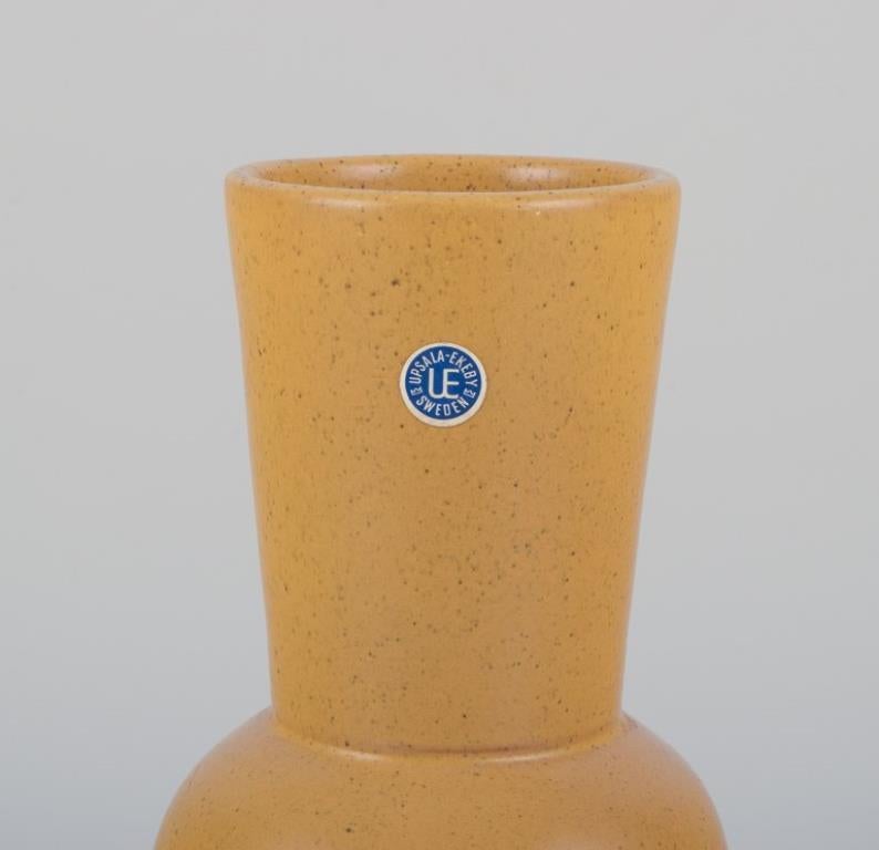 Mari Simmulson (1911-2000) pour Upsala Ekeby, Suède. 
Vase en céramique de style moderniste avec glaçure jaune ocre.
1960s.
Modèle 4078M.
Marqué. Avec Label.
En parfait état.
Dimensions : H 25,0 cm x P 9,0 cm : H 25,0 cm x D 9,0 cm.

Mari Simmulson