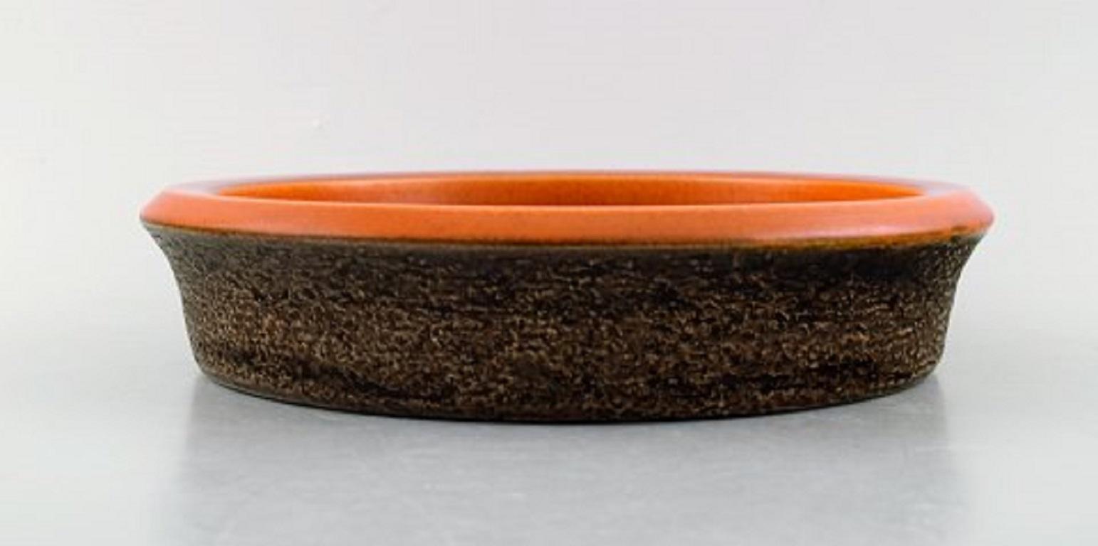 Mari Simmulson for Upsala-Ekeby. Dish in glazed stoneware. Glaze in brown and orange shades, 1960s.
In very good condition. Two minor glaze defects on the rim.
Measures: 23 x 5 cm
Stamped.