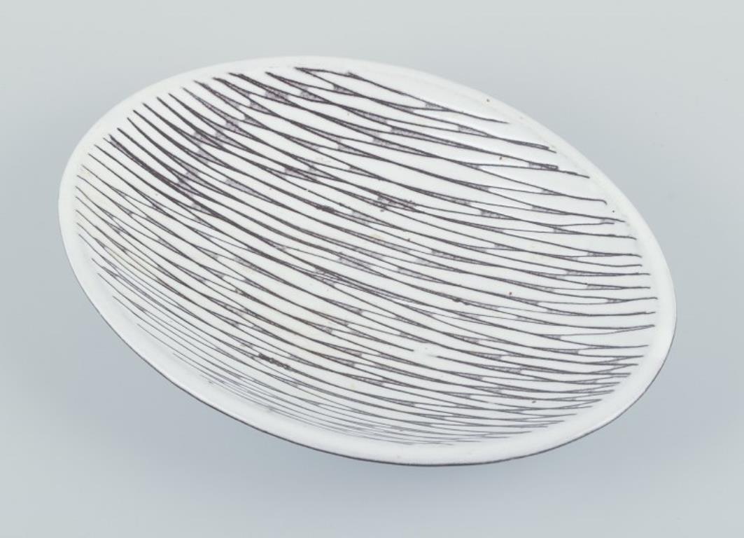 Mari Simmulson (1911-2000) for Upsala Ekeby. 
Low ceramic bowl. Decorated with lines.
Circa 1960.
Model number: 4089.
Marked.
In perfect condition.
Dimensions: W 25.0 cm. x H 4.0 cm.


Mari Simmulson (1911-2000) is recognized as a prominent figure