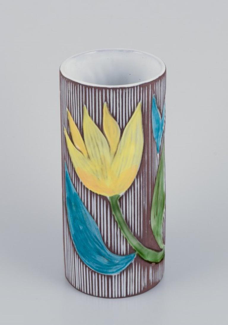 Mari Simmulson (1911-2000) for Upsala Ekeby, Sweden. 
Ceramic vase with floral motifs. Polychrome glaze.
Approximately from the 1960s.
Marked.
In perfect condition.
Dimensions: H 19.9 cm x D 8.8 cm.

Mari Simmulson is recognized as a prominent