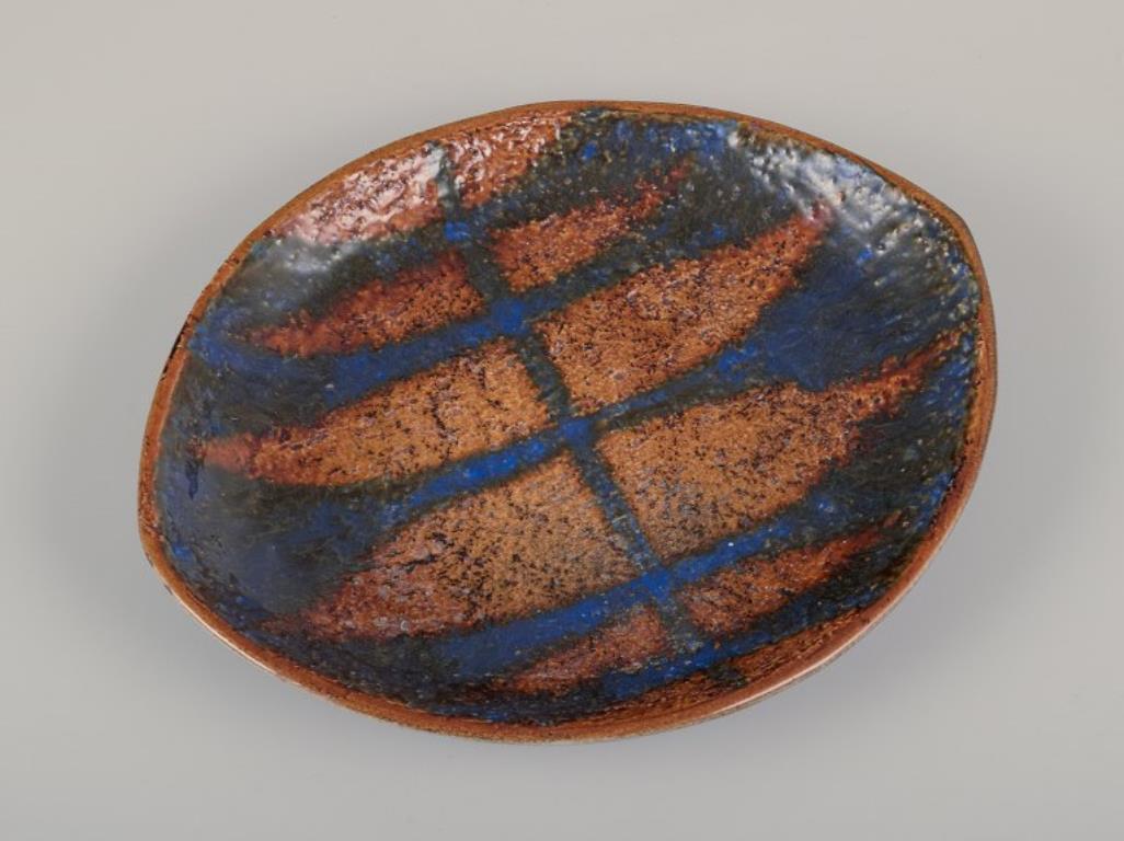 Mari Simmulson (1911-2000) for Upsala Ekeby, Sweden. 
Low ceramic bowl with glaze in blue and ochre tones.
Model: 4463.
Approximately from the 1960s.
Marked.
In perfect condition.
Dimensions: W 21.5 cm x D 18.0 cm x H 3.0 cm.