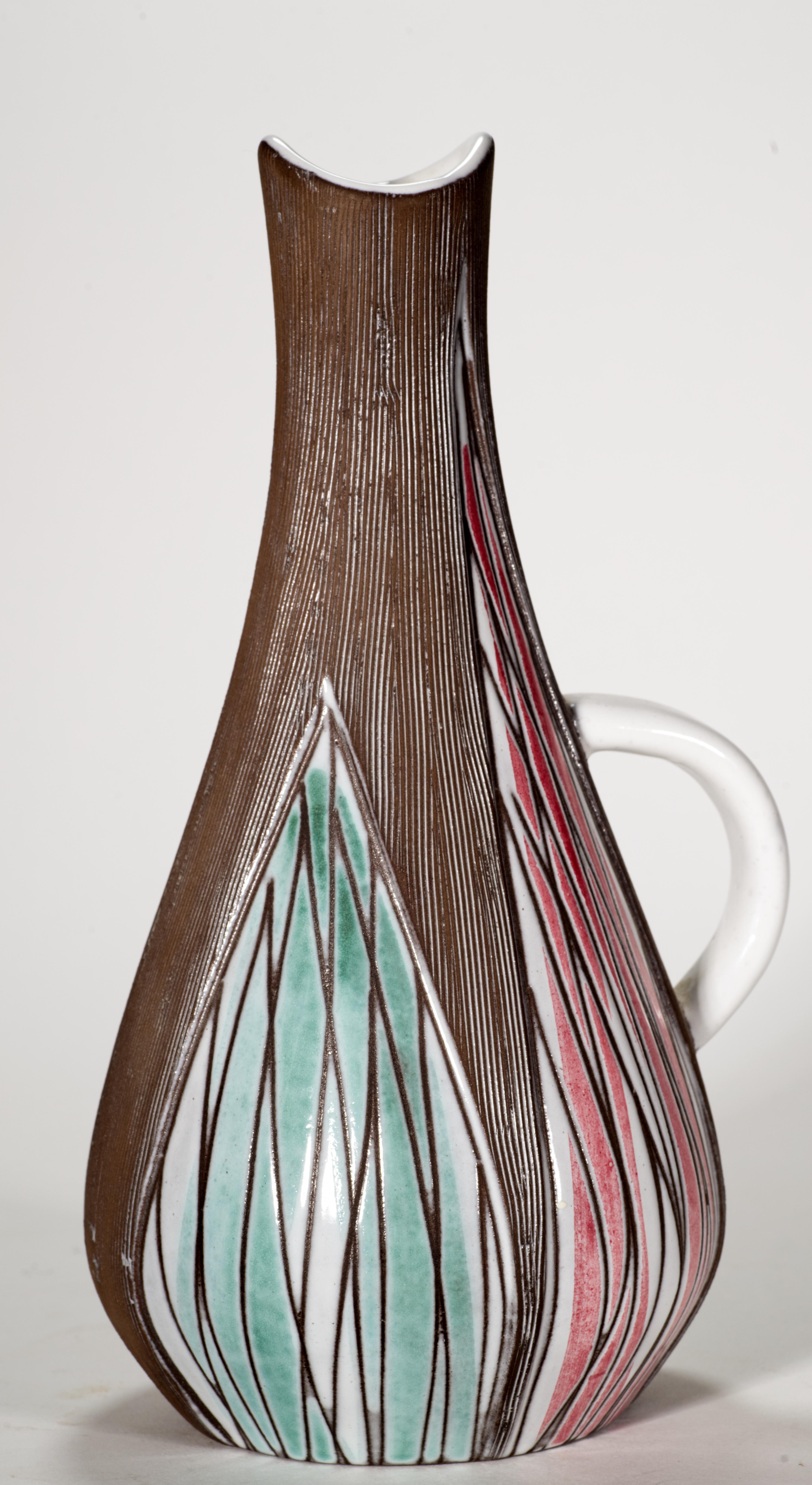 Il vaso modernista in ceramica con manico è stato disegnato da Mari Simmulson per Upsale-Ekeby come parte della serie Sagina nel 1959. Ha una forma minimale e dolcemente rigonfia, enfatizzata da un decoro astratto in tecnica sgraffito con texture