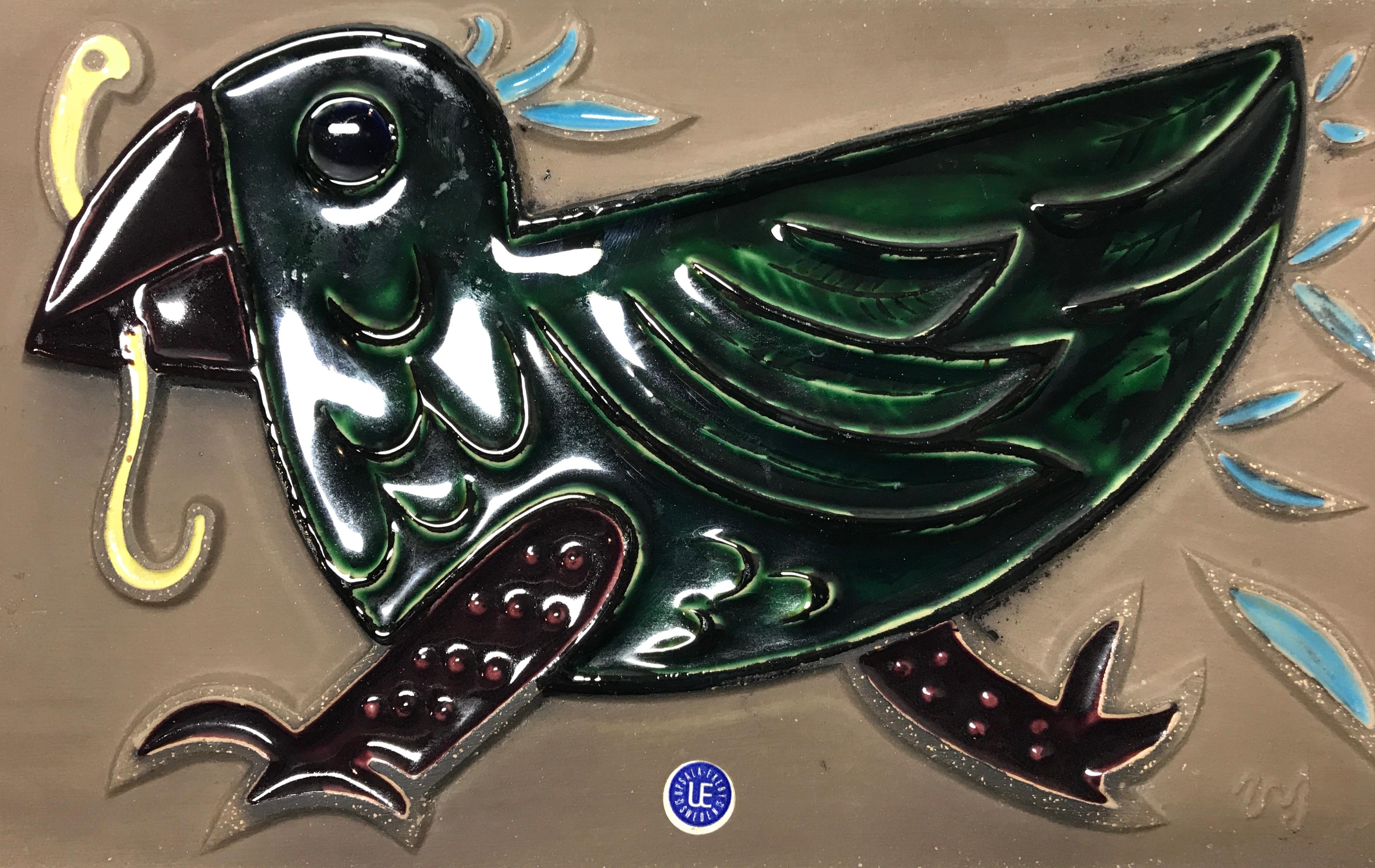 Delightful and fun, vintage ceramic wall plaque of an 'early bird who has caught the worm', by illustrious designer Mari Simmulson for Upsala Ekeby, Sweden
Decorated predominantly with a rich dark green enamel glaze in relief, on a matte