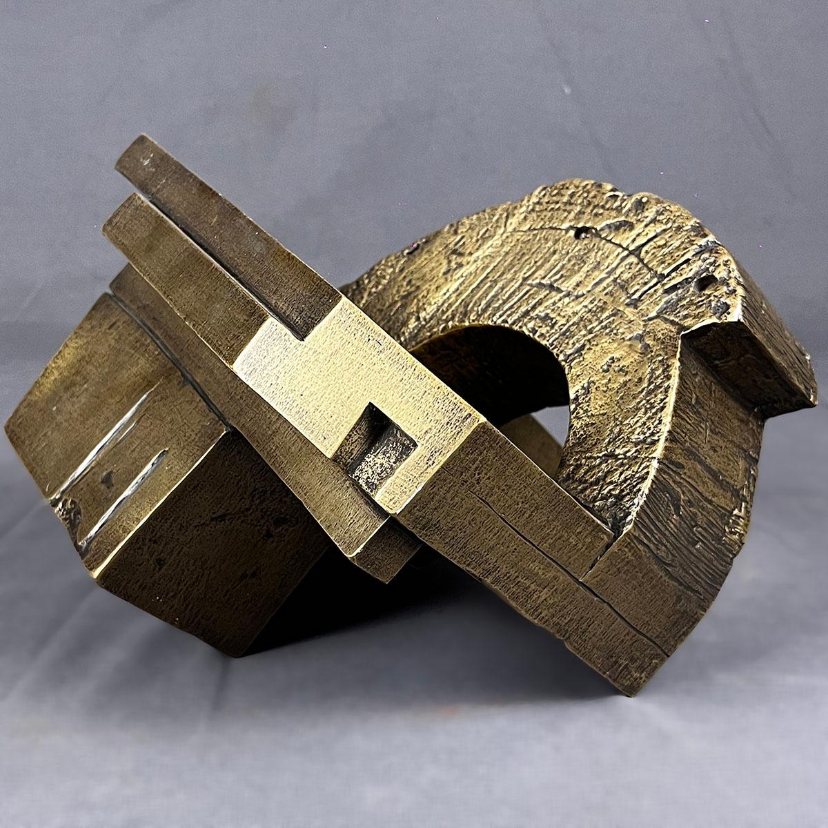 A geometric Brutalist style cast bronze sculpture by Spanish artist María José de Simón. The sculpture depicts a piece of wood log mounted over a geometric structure. The piece is unsigned. 

