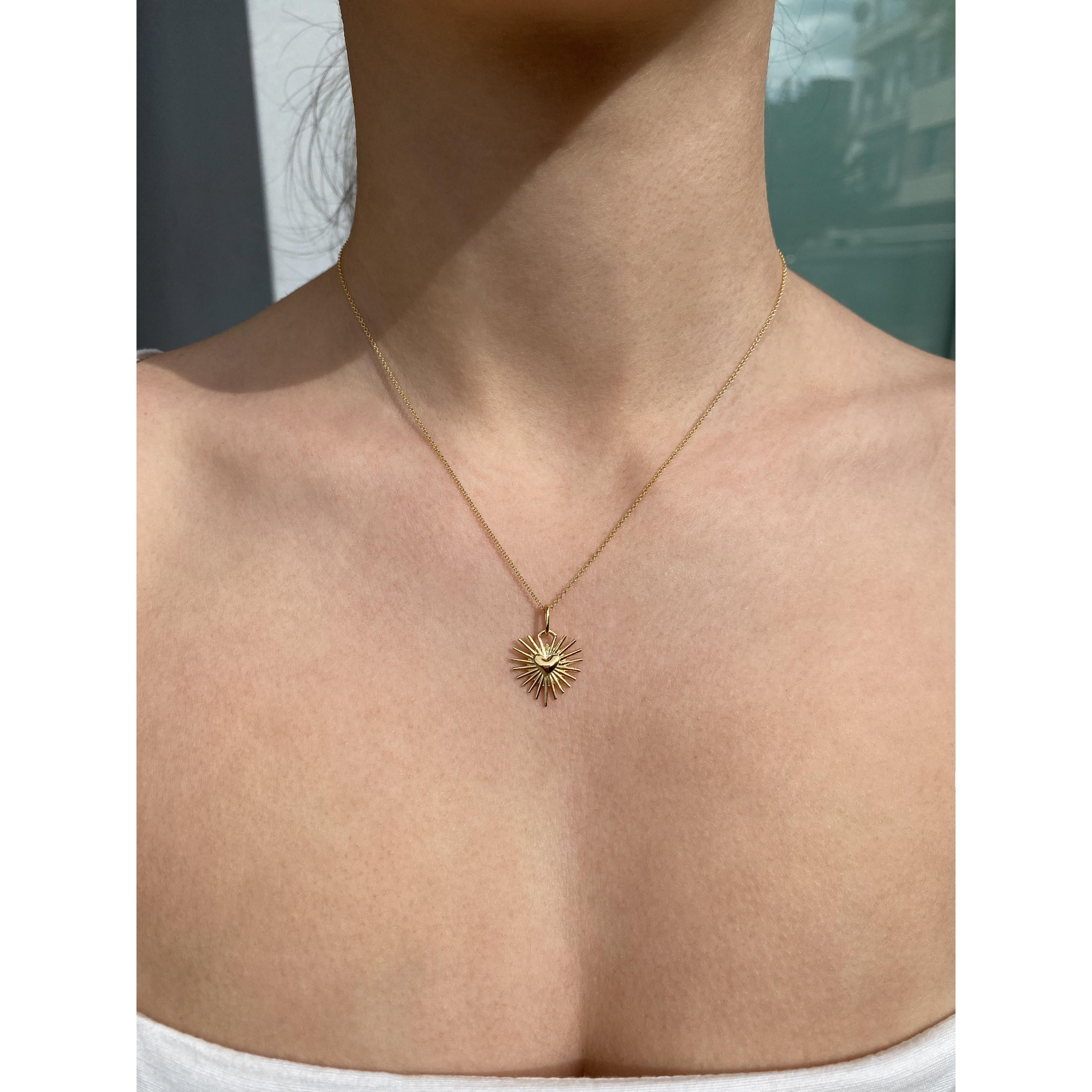 The ‘Radiating heart’ charm pendant, necklace is crafted in 18K gold hallmarked in Cyprus. The cute little heart charm pendant with 22 rays, is suspended from a delicate, 40 cm long, link chain. Twenty two is symbolic of fulfilment and