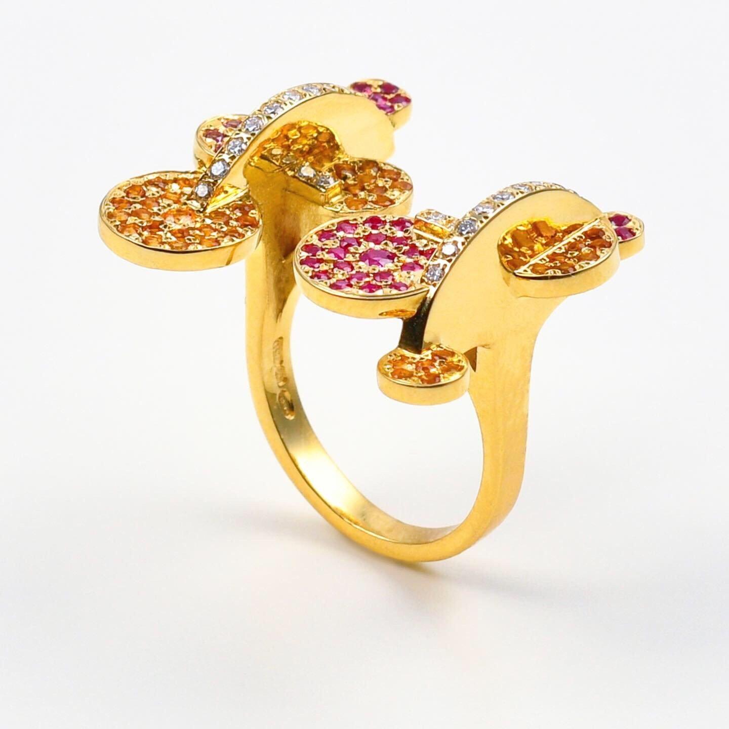 The 'Exploding Disk’, ring is crafted in 18k gold, hallmarked in Cyprus. This stunning, open, sculptural ring, comes in a highly polished finish and features Rubies 0,35 Cts, Rhodolites 0,12 Cts, Madeira Citrines 0,45 Cts and Diamonds 0,24 Cts. The