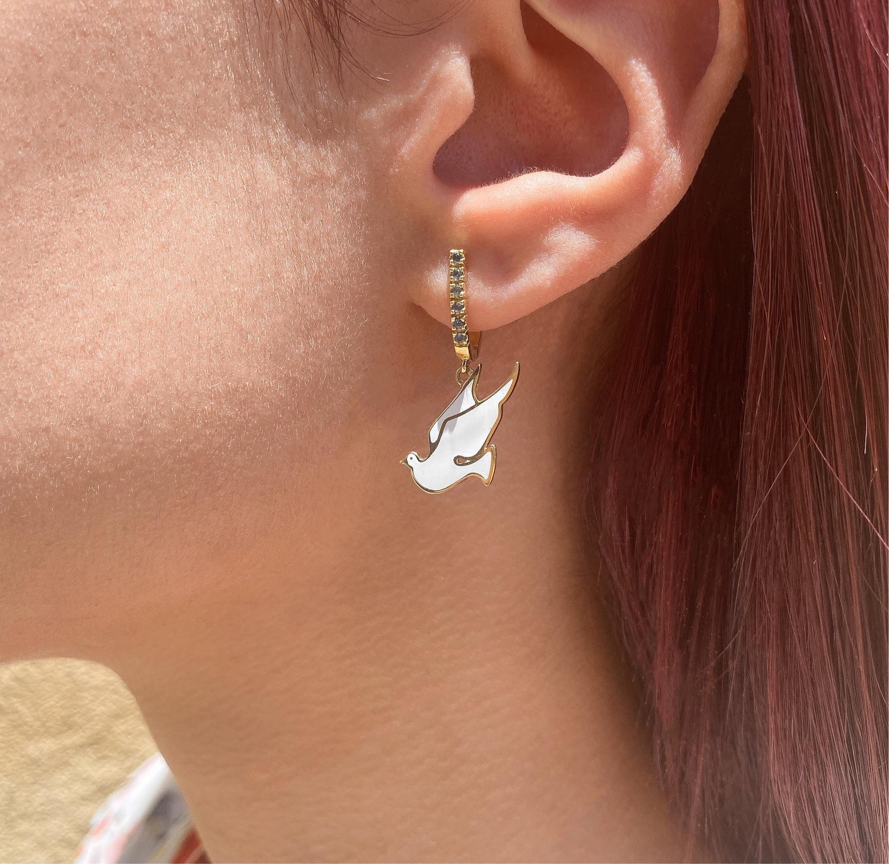 The Flying Dove, ear pendants are crafted in 18K yellow gold, hallmarked in Cyprus. These elegant ear pendants come in a highly polished finish and feature 0.2 cts of London Blue Topazes and white enamel, making them classy.  Being very comfortable
