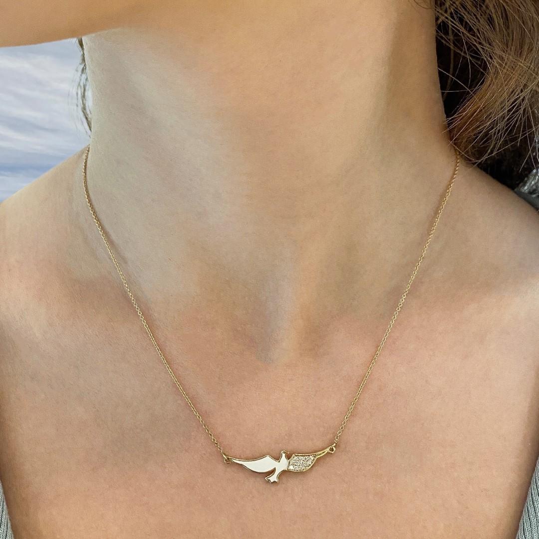 The Flying dove, enamel and diamond necklace is crafted in 18K yellow gold, hallmarked in Cyprus. This delicate, statement necklace comes in a highly polished finish with white enamel and features 0.10 Cts of White Diamonds, adding a touch of
