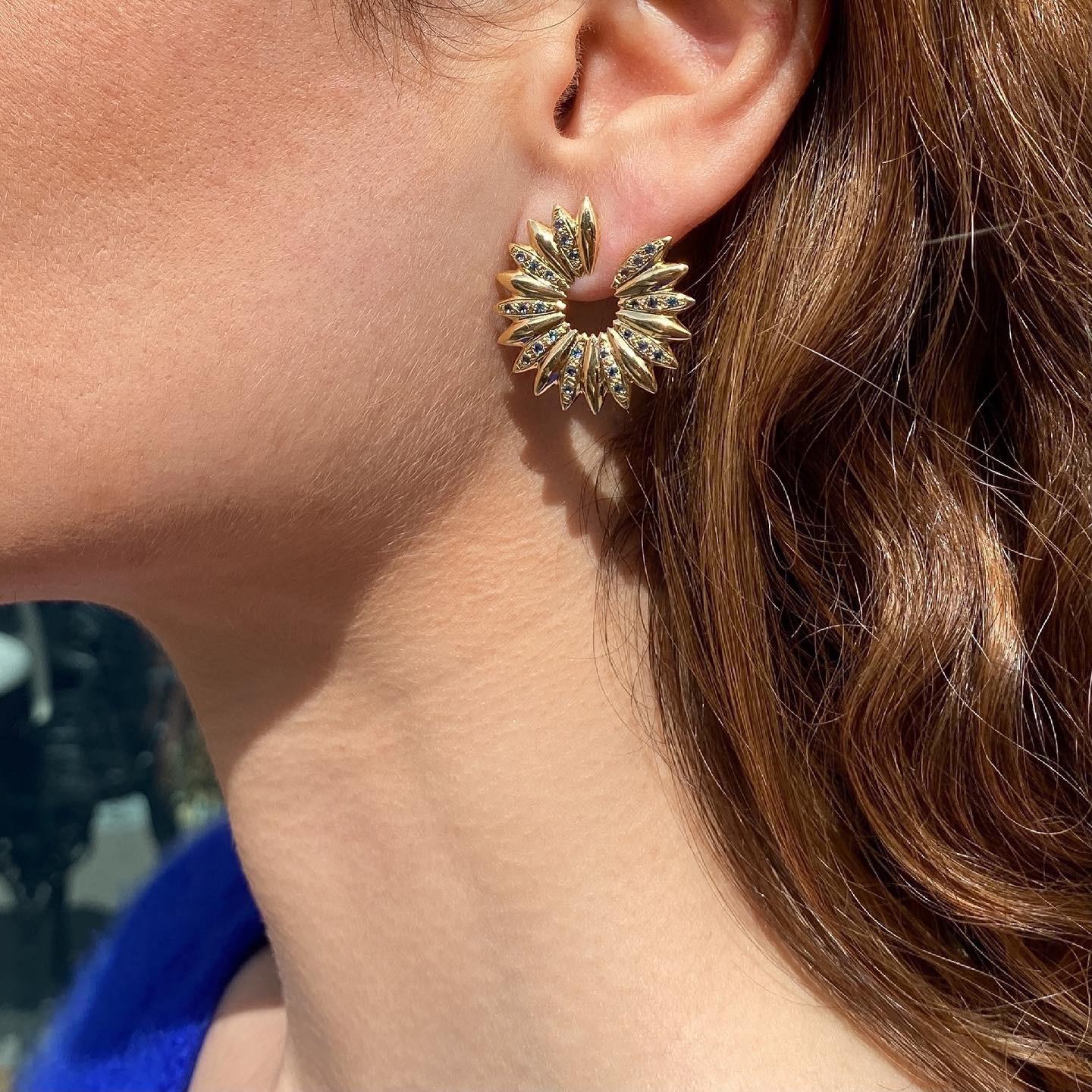 The ‘Grain array’ hoop earrings are crafted in 18K gold hallmarked in Cyprus. This striking pair of earrings, comes in a highly polished finish and features London Blue Topaz totaling 0,70 Cts. The clips at the back ensure a comfortable and secure