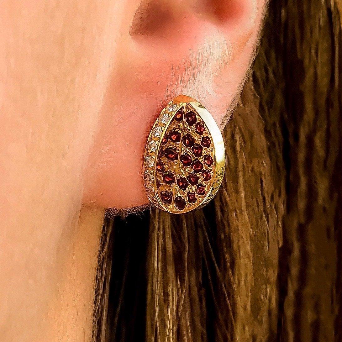 The 'Reflection’, ear studs are crafted in 18k gold, hallmarked in Cyprus. These discreetly impressive sculptural ear studs come in a highly polished finish and feature Red Garnets, 0,3 Cts and white, VS Diamonds, 0,18 Cts. The 'Reflection’, ear