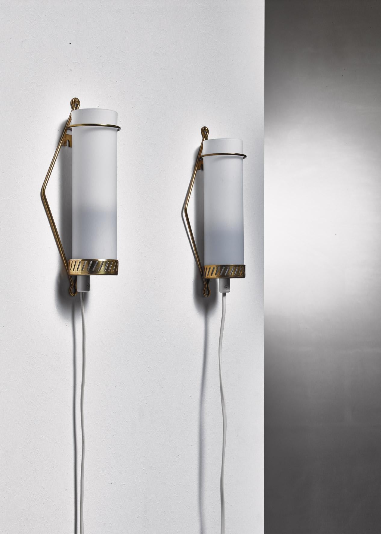 A pair of model K8-25 wall lamps designed by Maria Lindeman for Idman. The lamps are made of a brass frame with a cylindrical opaline glass shade. Marked by Idman.