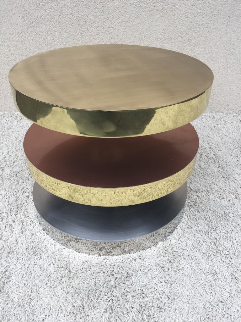 In the style of Maria Pergay for three-tiered swivel table. Steel, copper and brass construction with wheels under base. Very heavy. Handmade. Versatile Design many uses-with versatile arrangements end table, coffee table, pedestal table, display.