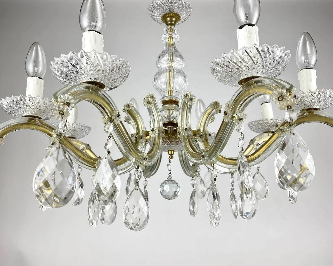 Circa 1970s Maria Theresa style chandelier with eight candle arms.

Germany.

The framework is in golden brass, surrounded by 100 % transparent crystal that capture and reflect the light of the candle bulbs.

There are 8 lights and a profusion