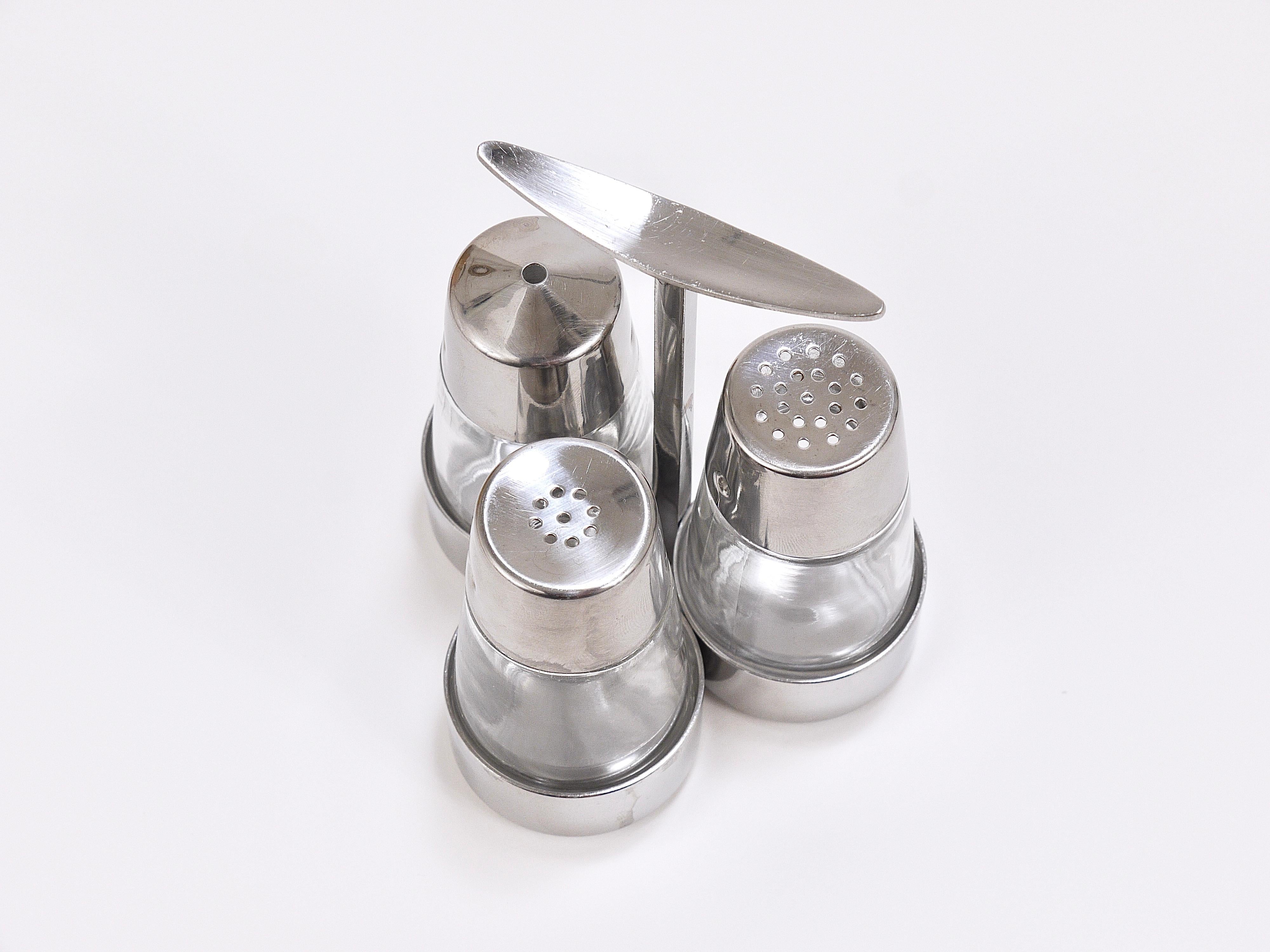 A very stylish modernist cruet set from the 1960s. Designed by the German artist and designer Marianne Denzel, executed by Berndorf Austria. Consist of a stainless steel holder / stand with a beautiful handle, salt and pepper shakers and a toothpick
