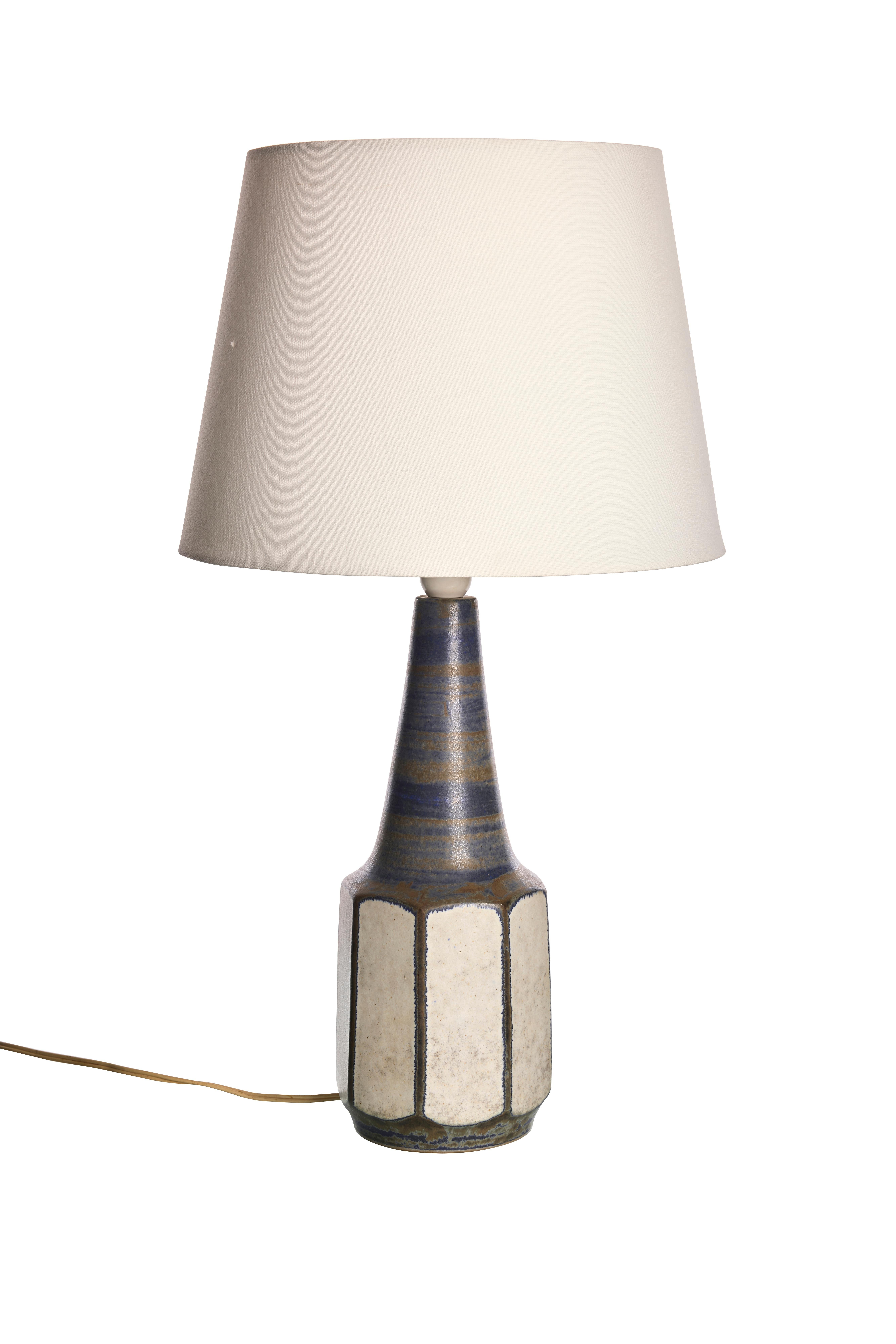 Add a touch of Scandinavian sophistication to your space with this unique stoneware lamp by Marianne Starck.

The lamp features a beautifully glazed base with a distinctive geometric pattern, blending earthy tones of blue and beige. The