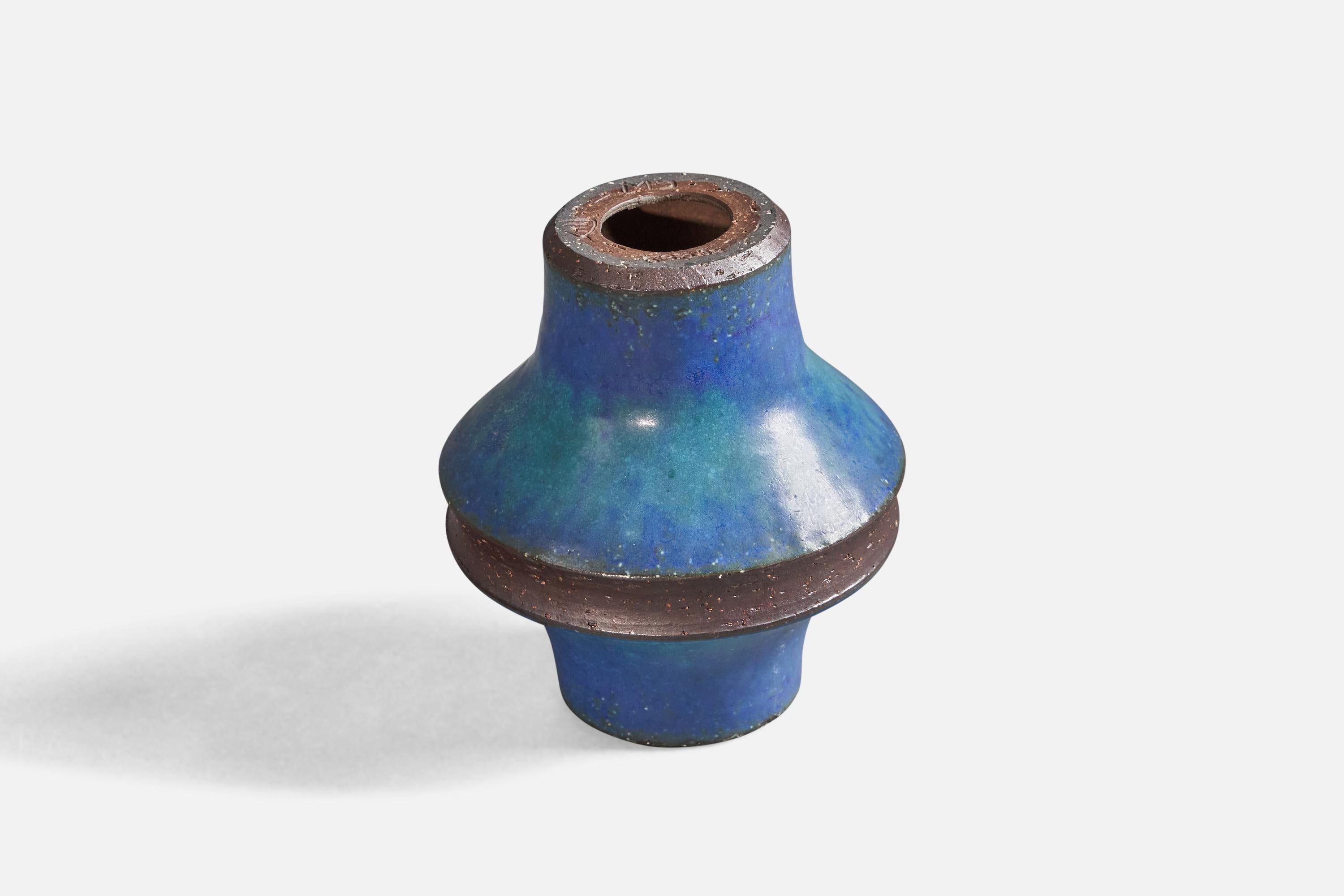 A semi-glazed blue stoneware vase, designed by Marianne Starck, and produced by Michael Andersen, Bornholm, Denmark, c. 1960s.

 With signature and stamps to top edge. Vase can be reversed and used as a candle stick.
