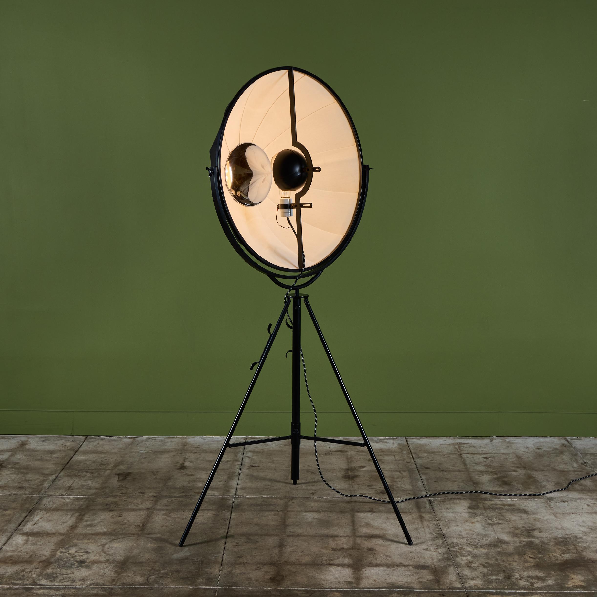 Mariano Fortuny Photographer floor lamp, c.1980s, Italy. The floor lamp is constructed of a black steel tripod frame with a two toned black and white cotton lamp shade. The shade swivels left to right. The bulb is hidden behind a black steel