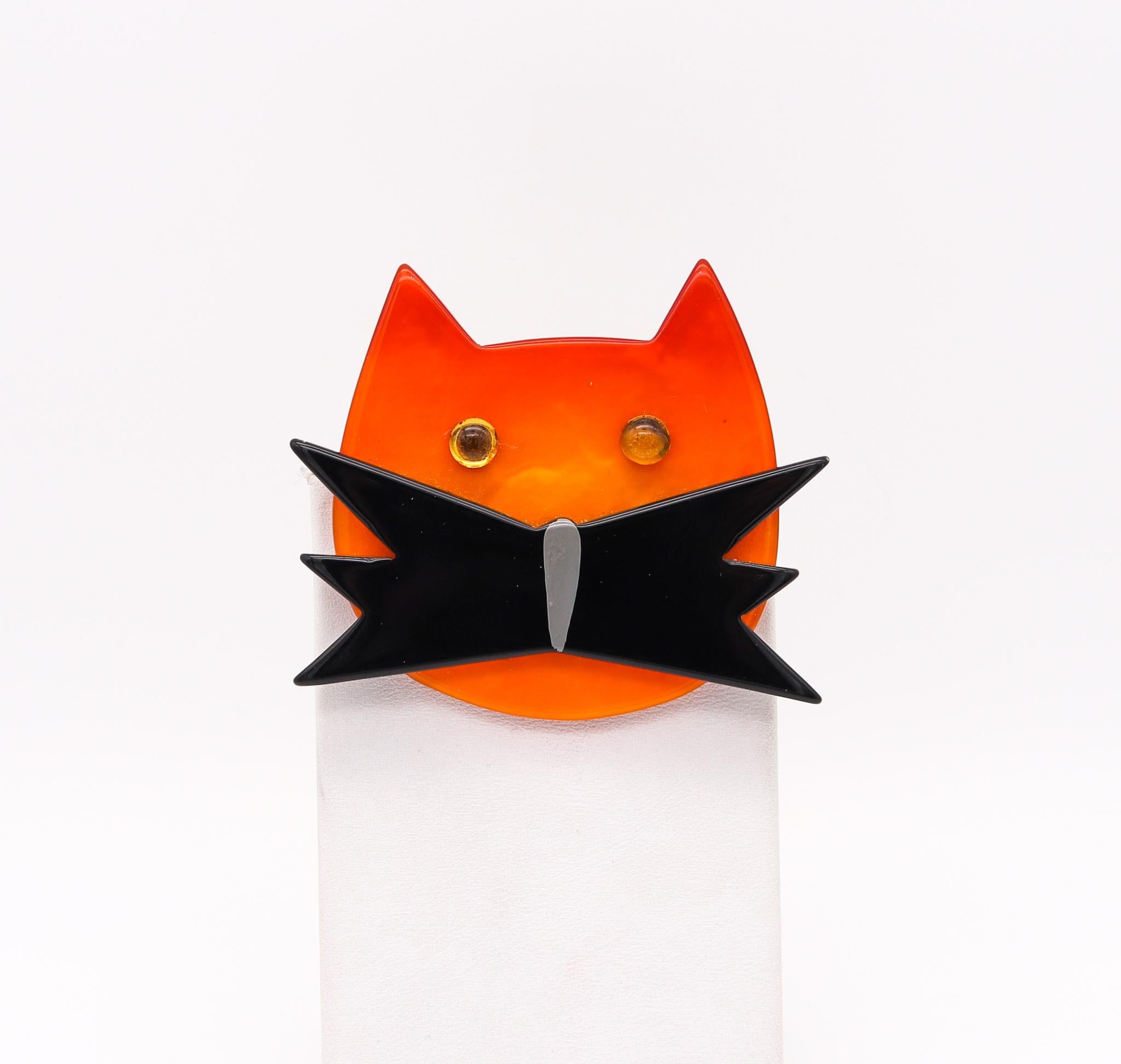 A cat brooch designed by Marie Christine Pavone.

Add some quirk to your brooch collection with our adorable cat brooch from Marie Christine Pavone. Cat constructed from contrasting black and orange bakelite and accented with two orange rhinestone