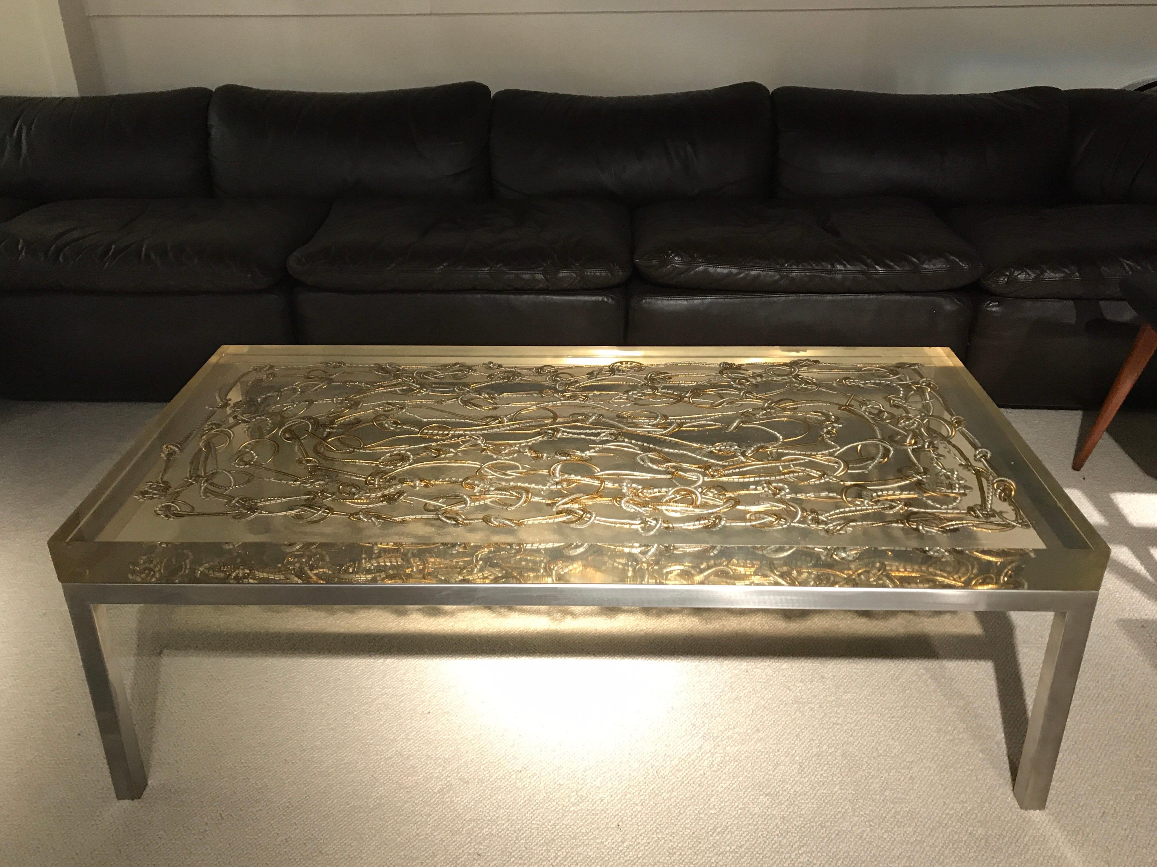 1970s Marie Claude de Fouquieres coffee table with resin top.
Metal pieces inlaid on resin
Brushed steel feed.