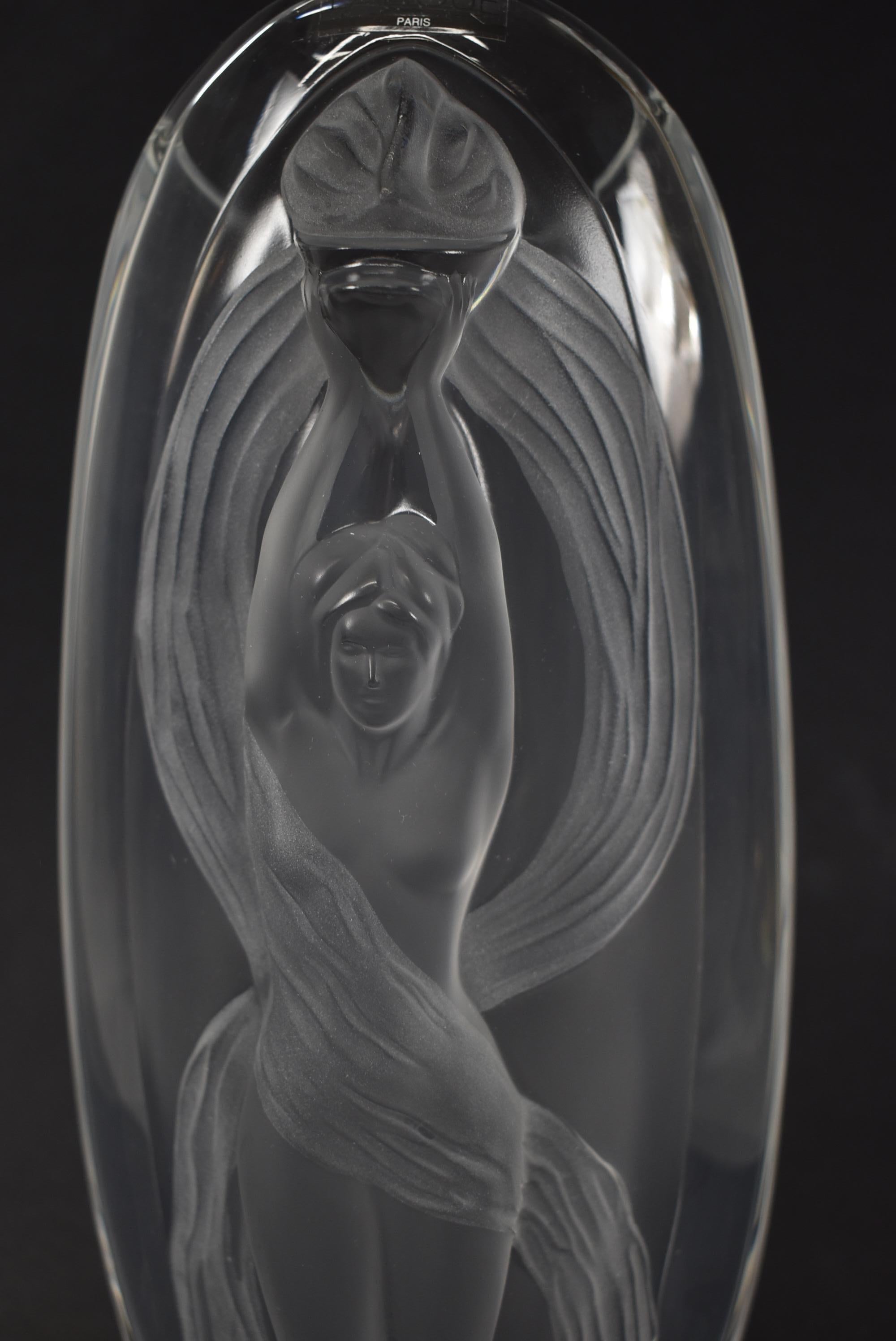 Lalique Eroica transparent and satin finished crystal slender body of a woman holding the flame of triumphant Liberty sculpted on the surface of an oblong vase. Very nice condition with no chips or scratches. Original box. Dimensions: 13.25