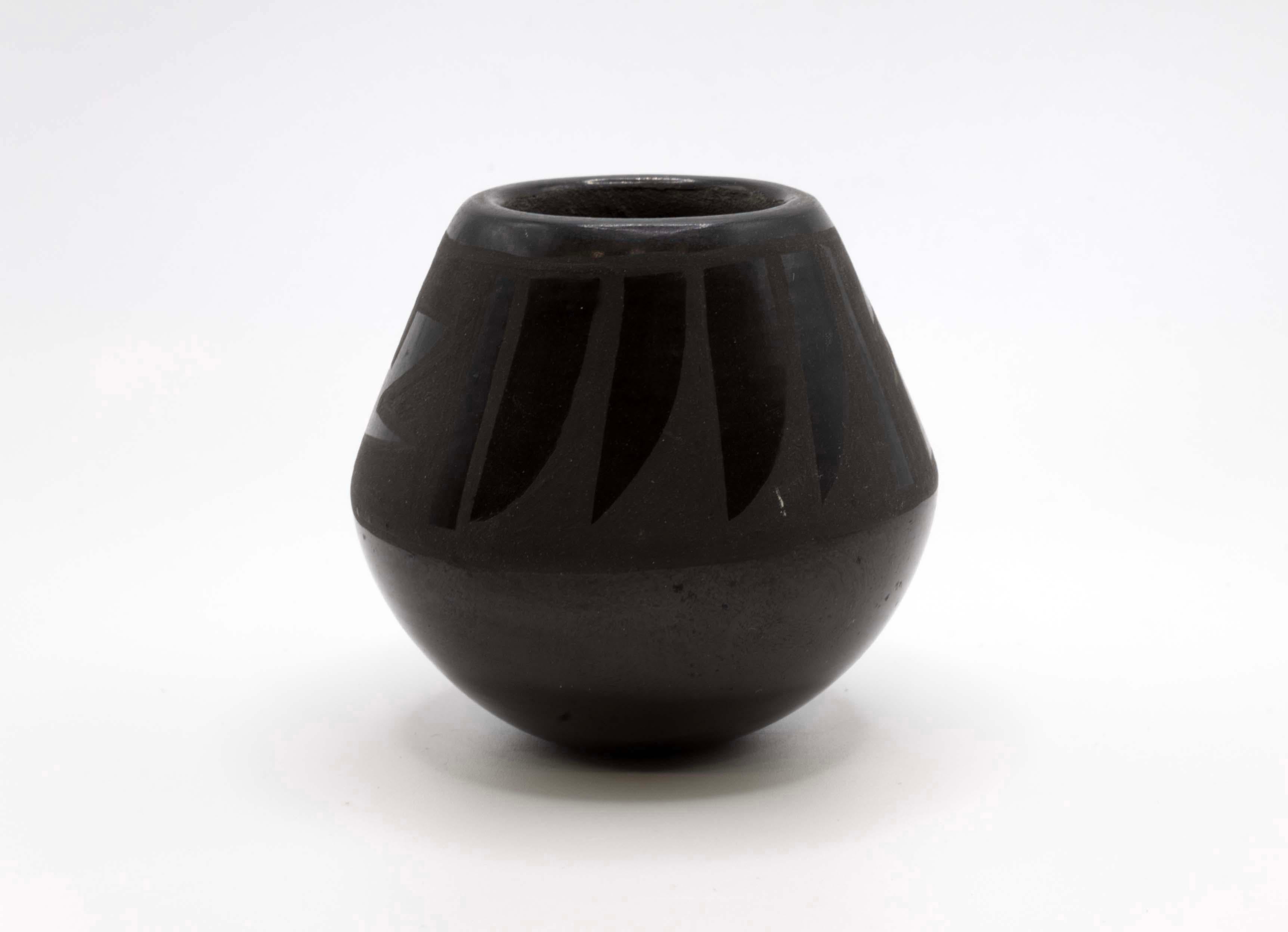 A miniature pair of Santa Clara native pottery vessels with carved designs. Signed by Marie Naranjo and one signature is unknown. Santa Clara Pueblo is known for its black pottery designs. Natural red clay fired in an intricate process to create
