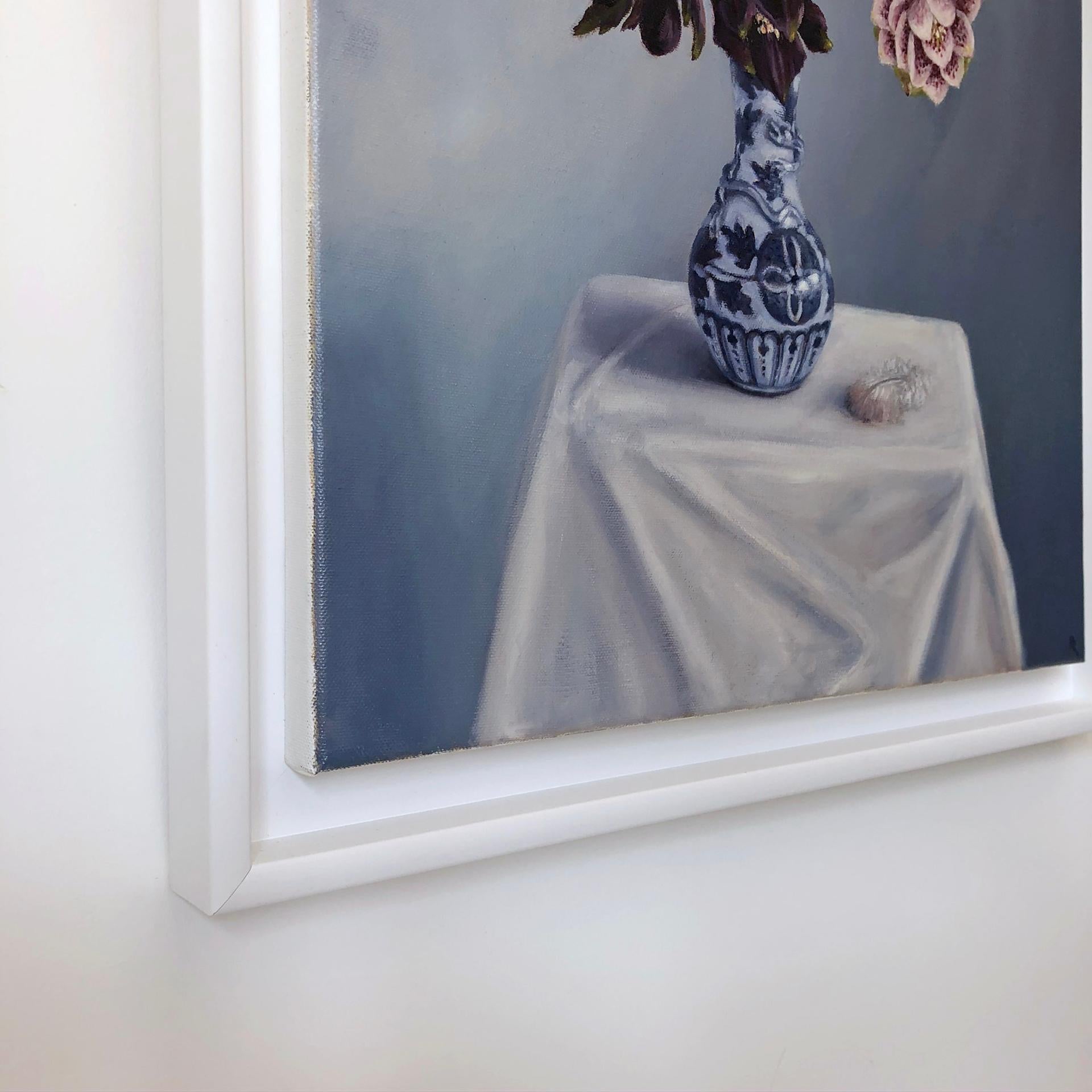 Marie Robinson’s Signs of Spring is an original still life painting of a blue and white china lizard dragon vase containing dark purple and white spotted Hellebore flowers. as they are sometimes called including mauve Scabious, purple Knapweed, and