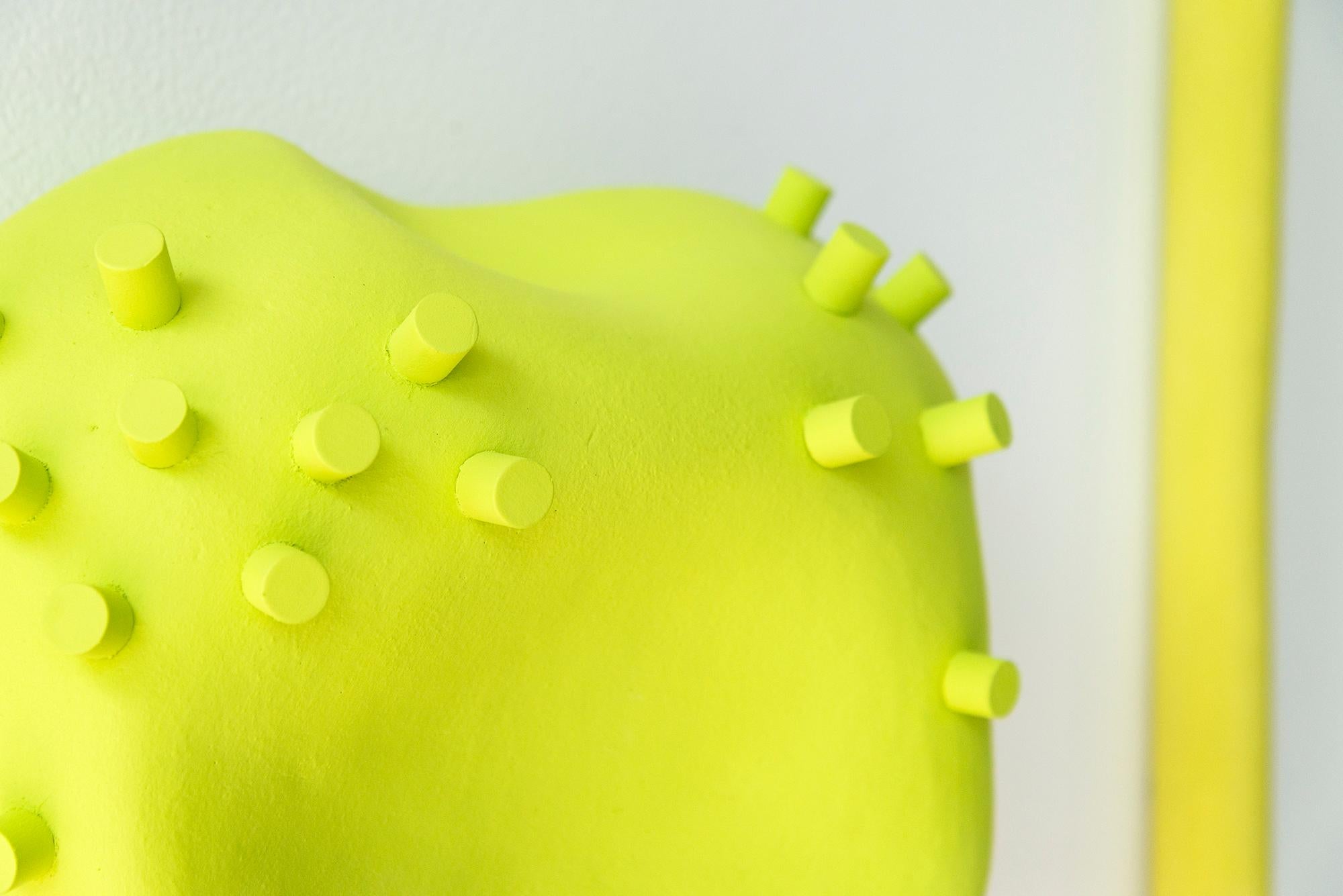 This modern minimalist wall sculpture is handmade in ceramic by Marie-Ève Fréchette. The three carefully curated objects—a rock-like form and two narrow pipes are handmade from porcelain and rendered in a bright, contemporary color palette of lime