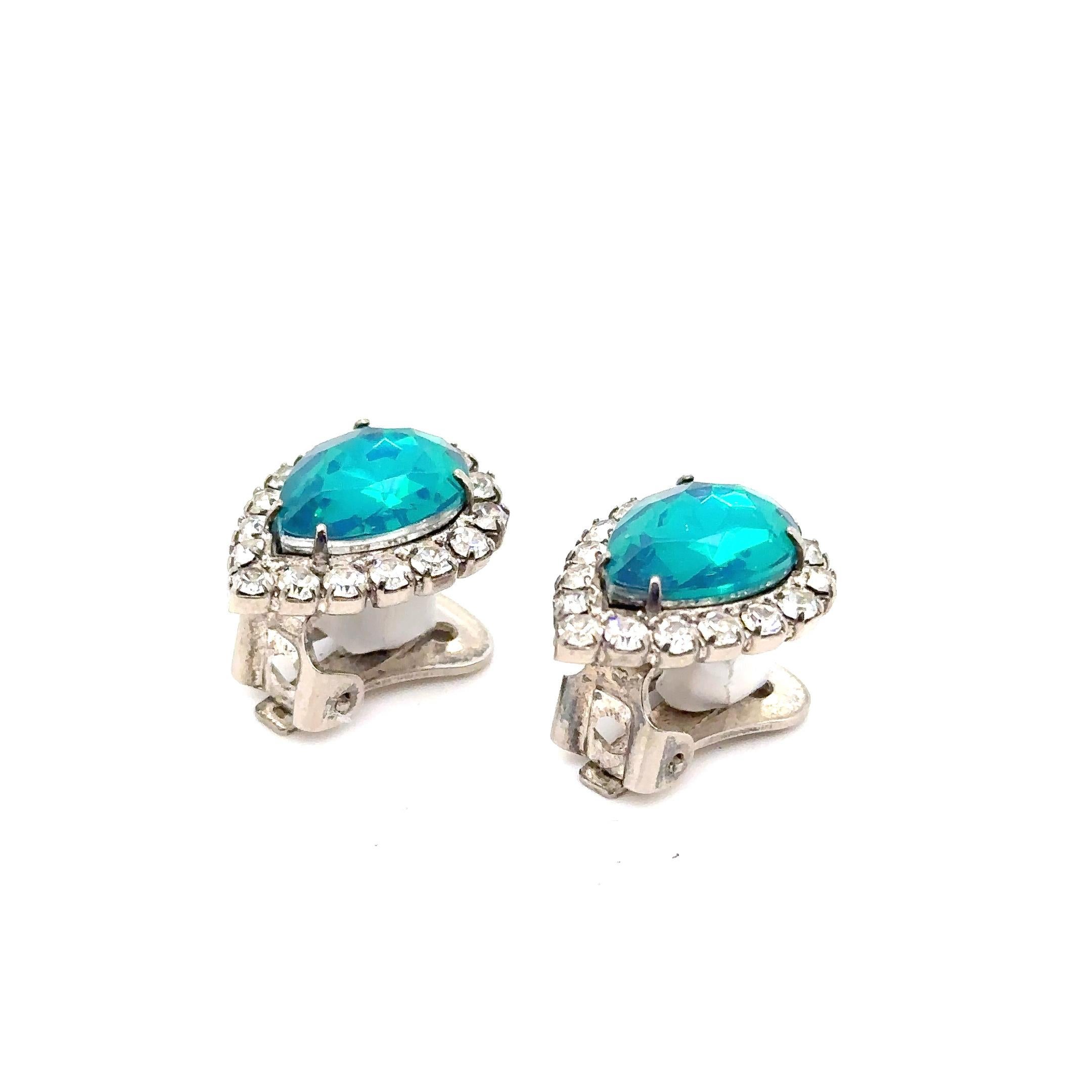 Earrings with large central blue green faux stones surrounded by faceted clear stones with clip on backs. 
7/8 inches
Experience the generosity and glamour of Marilyn Monroe with these stunning icy blue rhinestone earrings, lovingly gifted from her