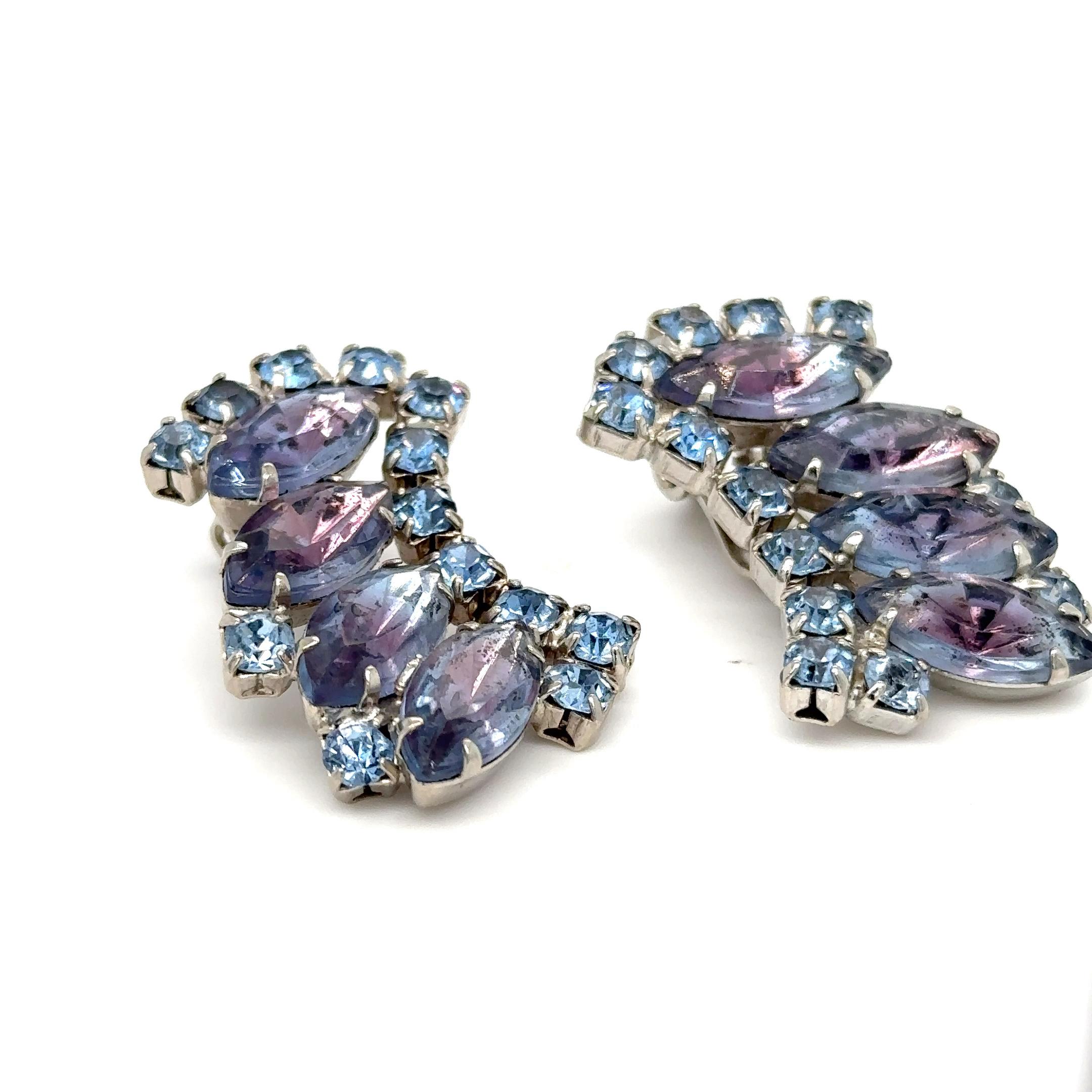 A pair of clip on earrings with marquis lavender stones surrounded by periwinkle round rhinestones. 
One clip missing. 
1 1/2 by 7/8 inches
Indulge in the enchanting allure of these mesmerizing blue and purple stones, beloved treasures from Marilyn