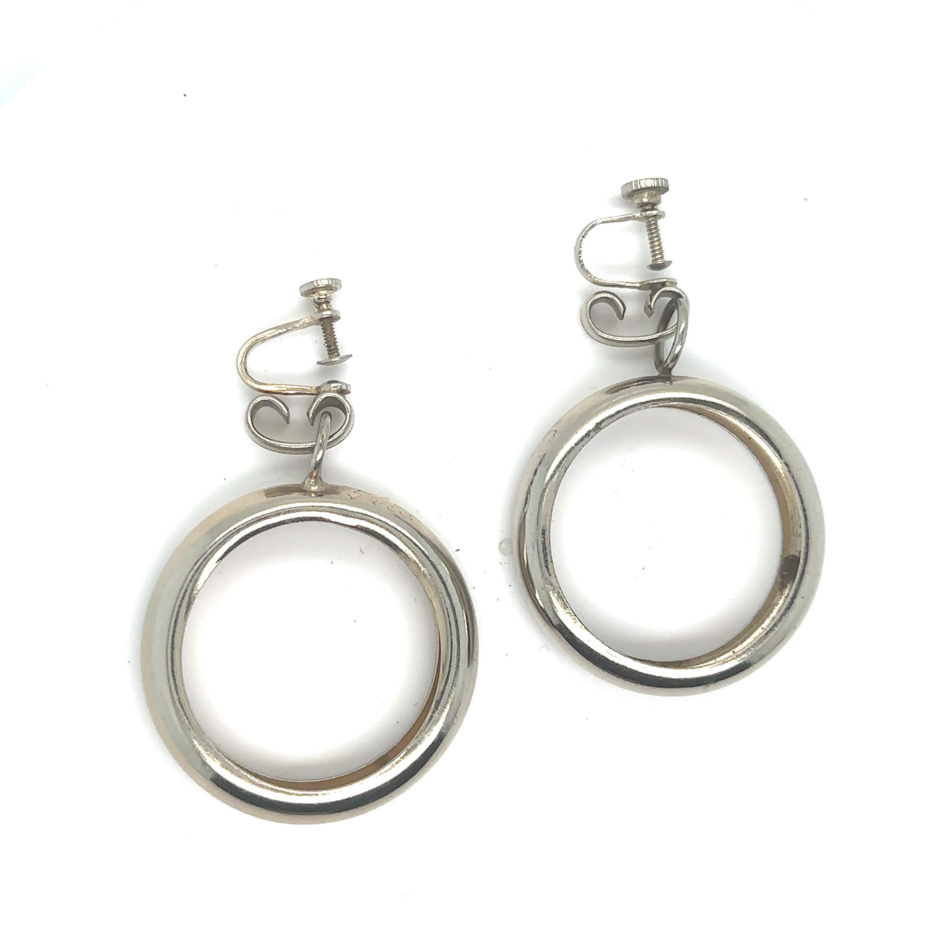 Silver metal hoop earrings with screw post backs the first with an impressed design on front of posts. 
2 inch drops
Whether gracing the silver screen or dazzling off-camera, Marilyn often adorned herself with these elegant hoops, adding a touch of