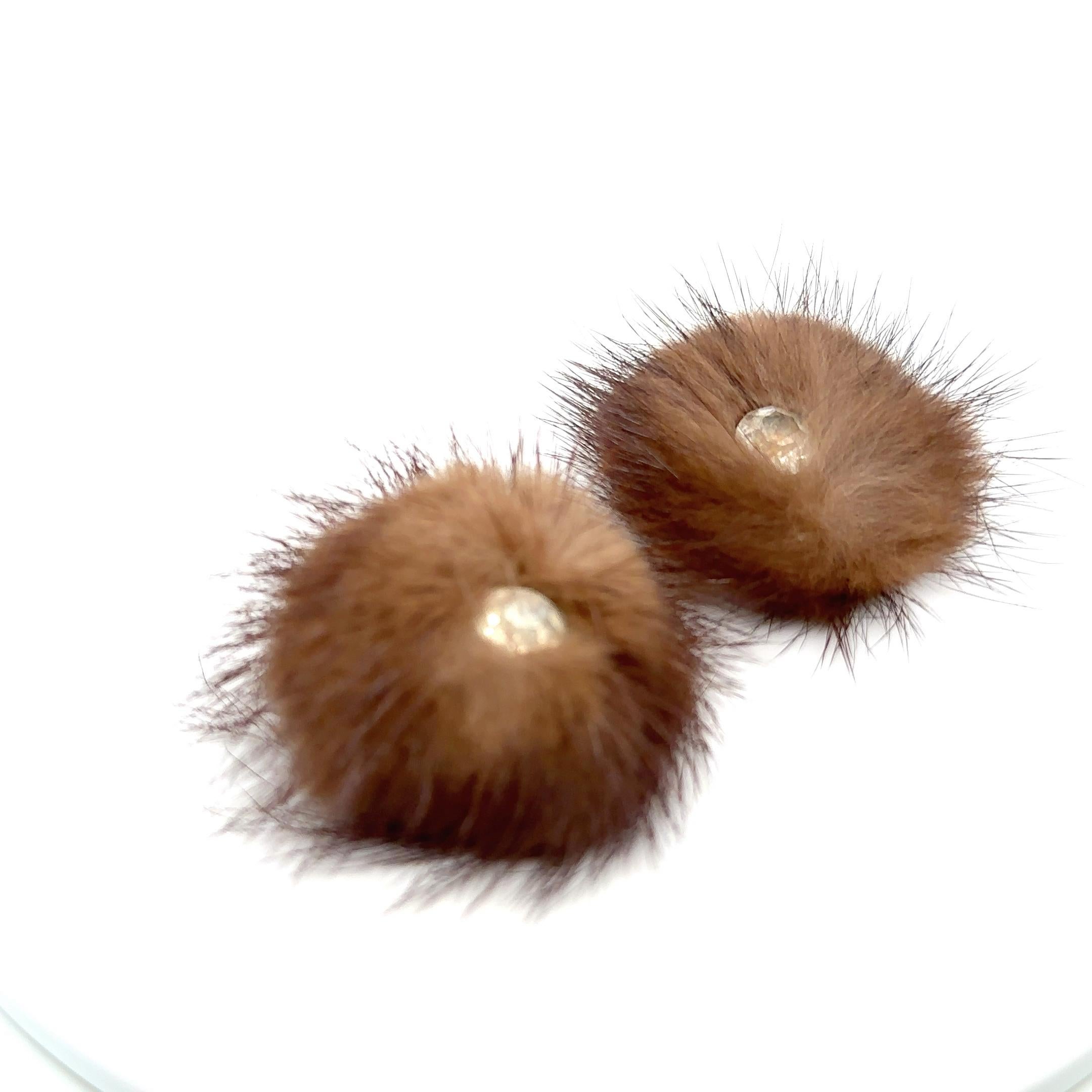 Mink earrings centering on single clear past stones with brass ear clips. 
1 3/4 inches
Step back in time to the glamorous 1950s with these exquisite mink earrings featuring dazzling rhinestone centers. A true conversation starter, these earrings