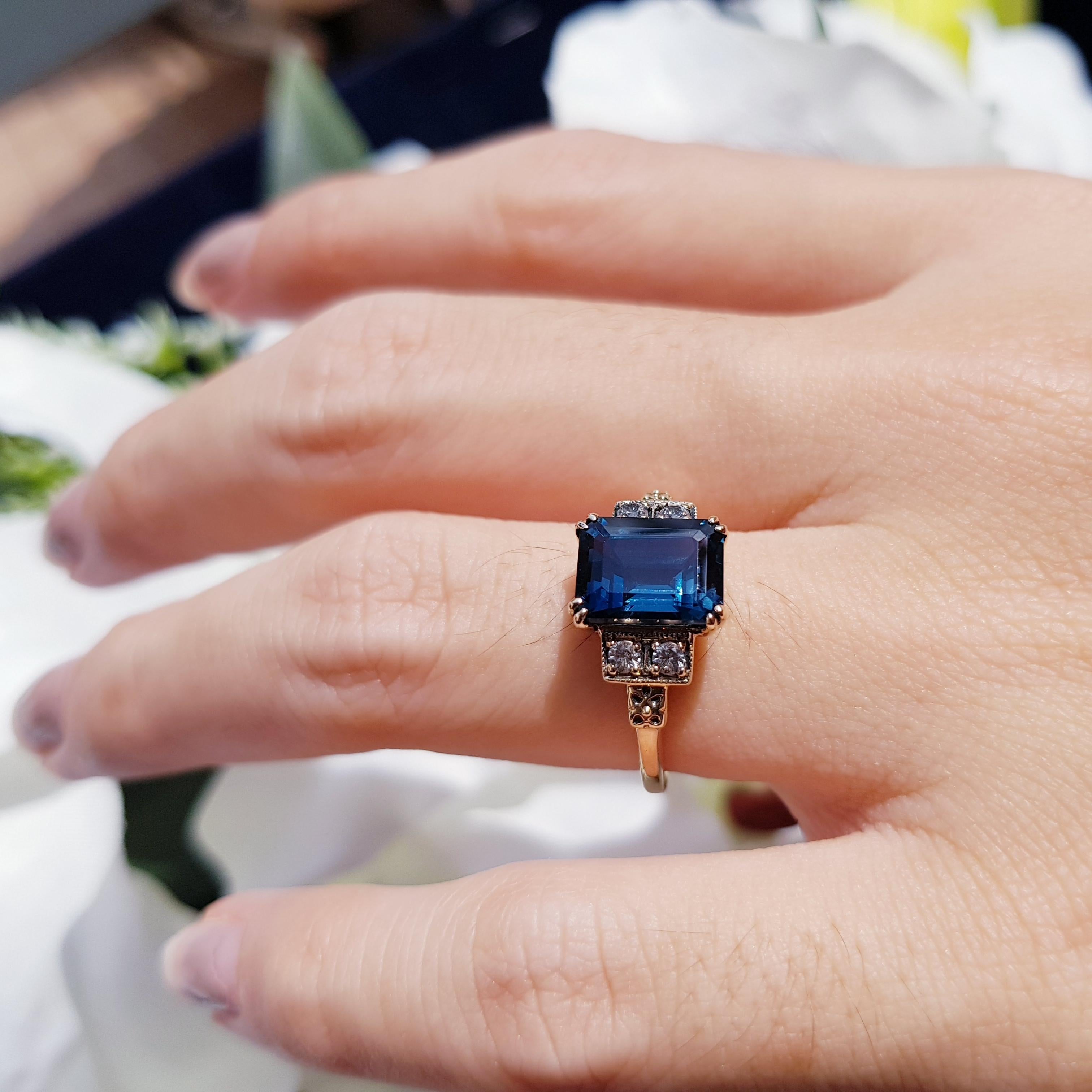 Elegantly refined, this gemstone and diamond ring showcases an emerald cut London blue topaz  complemented by four matching round white sapphires and set in enduring yellow gold.  

Ring Information
Style: Art Deco
Metal: 9K Yellow Gold 
Weight: