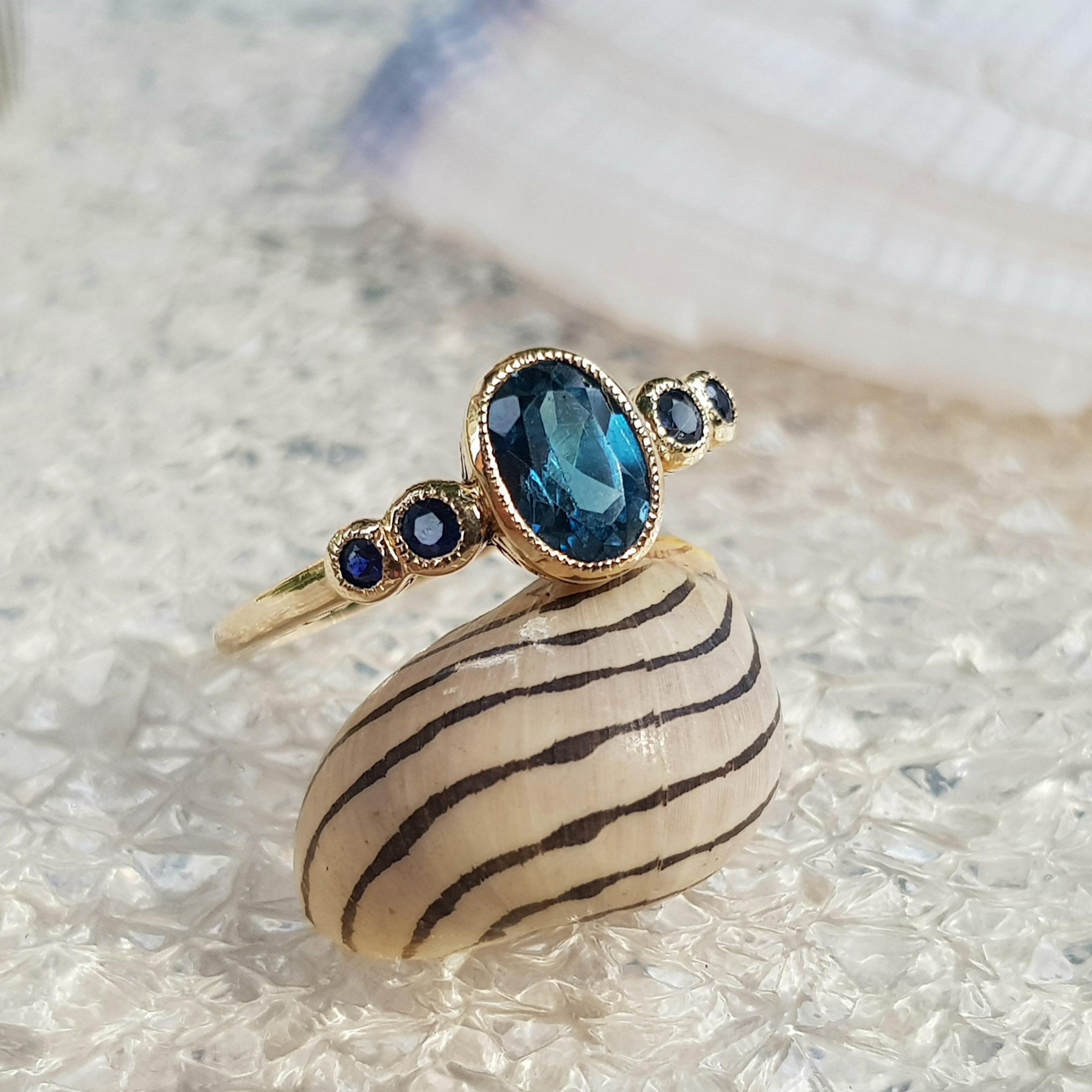 Simple and straightforward, this ring showcases sophisticated style. Fashioned in 9k gold, this ring showcases a stunning 7 x 5 mm. oval shaped London blue topaz and round sapphires on shoulders. A great look anytime, this ring finished with a