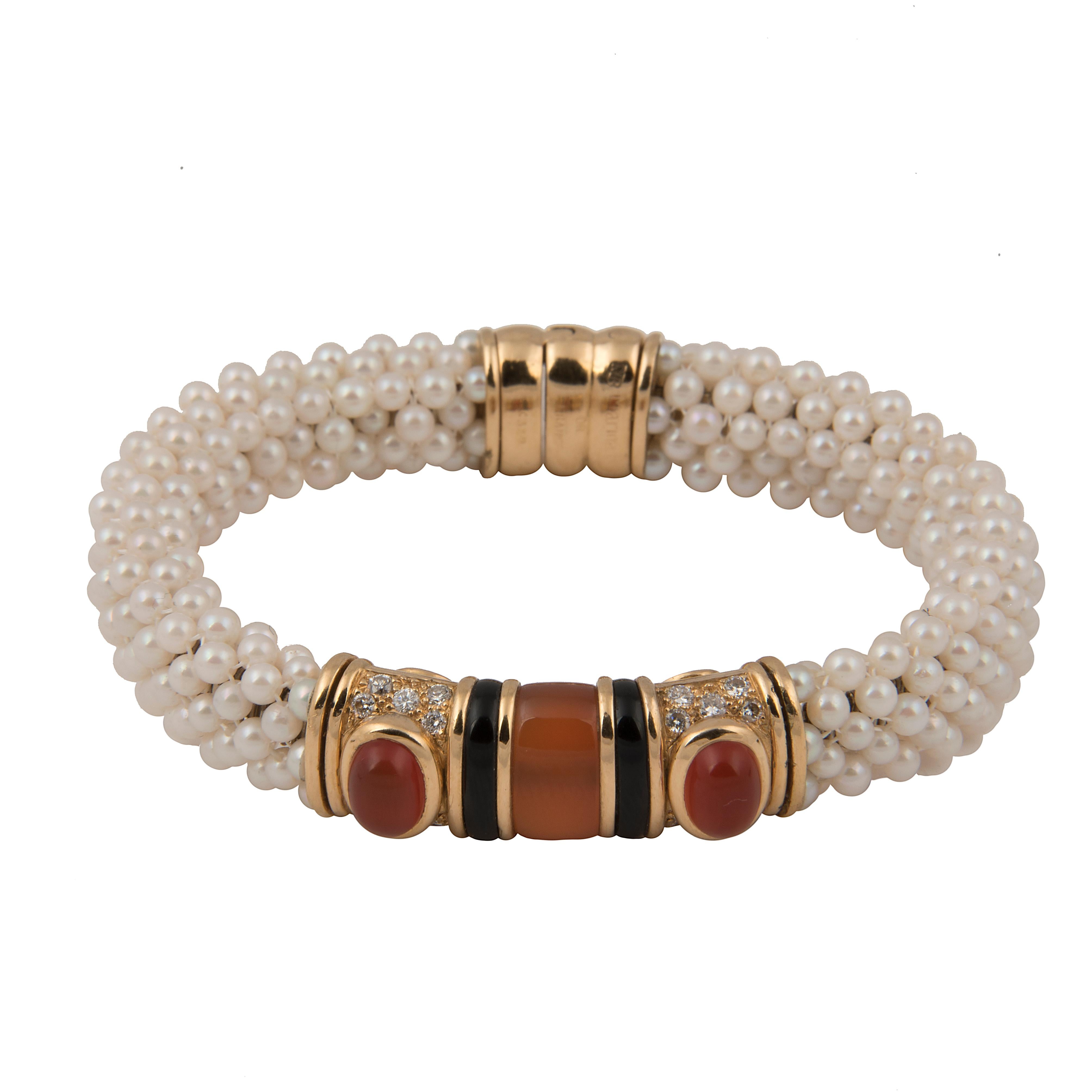 Bangle bracelet designed by Marina B (Bulgari). The band in braided cultured pearls on a stainless-steel spring, with an 18k yellow gold motif with onyx, pavé set diamonds and cornaline.
Signed Marina B, Maker's mark, French hallmarks and numbered