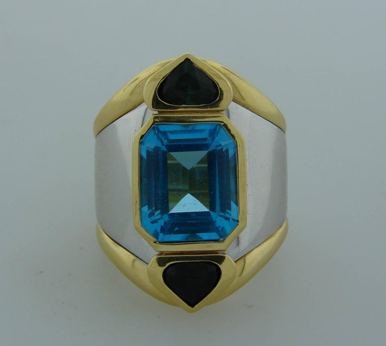 Bold and chic cocktail ring created by Marina B in the 1980's. It definitely makes a statement and would be a great addition to your jewelry collection. Features an emerald cut blue topaz, set in 18 karat yellow and white gold and accented with two