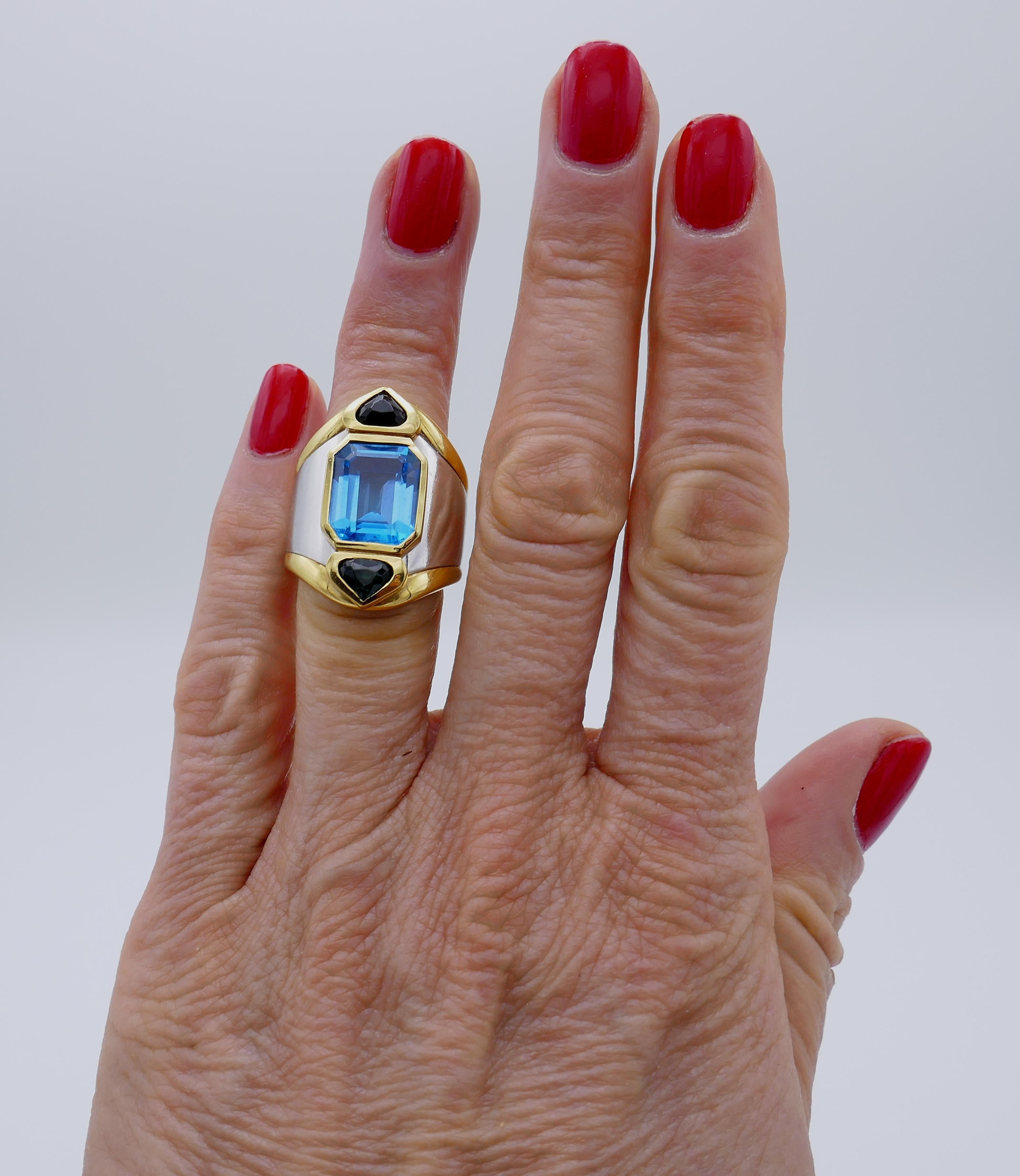 Bague de cocktail audacieuse et chic créée par Marina B dans les années 1980. Il s'agit d'un bijou qui a de l'allure et qui fera partie de votre collection de bijoux. Comprend une topaze bleue de taille émeraude, sertie en or jaune et blanc 18