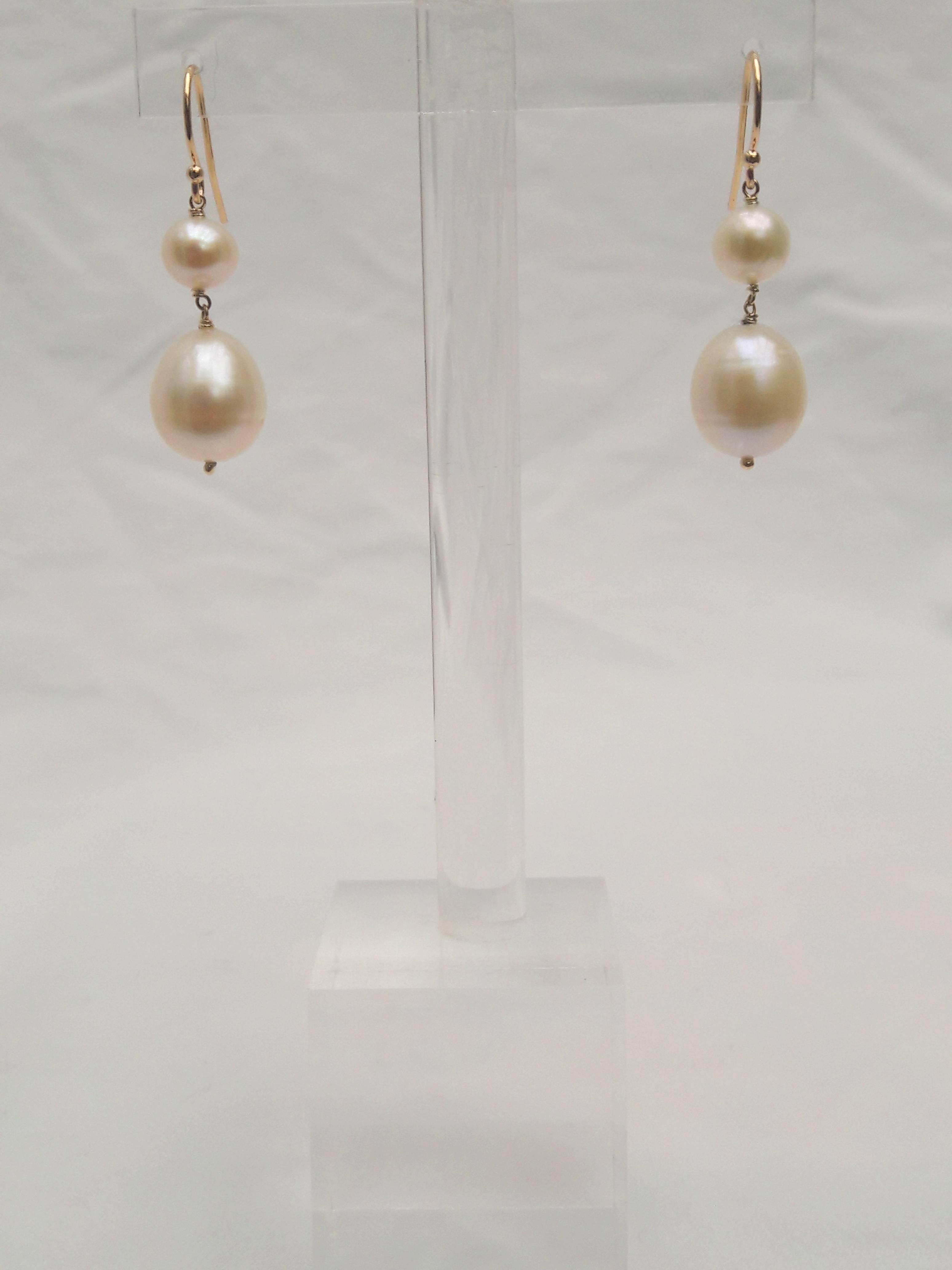 Elegant, yet understated.

These beautiful earring are composed of a pair of smooth white pearls suspended with gold findings. Dangling from a 14k yellow gold earwire, a 6mm round pearl sits atop a larger, oval shaped 11mm pearl. This classic