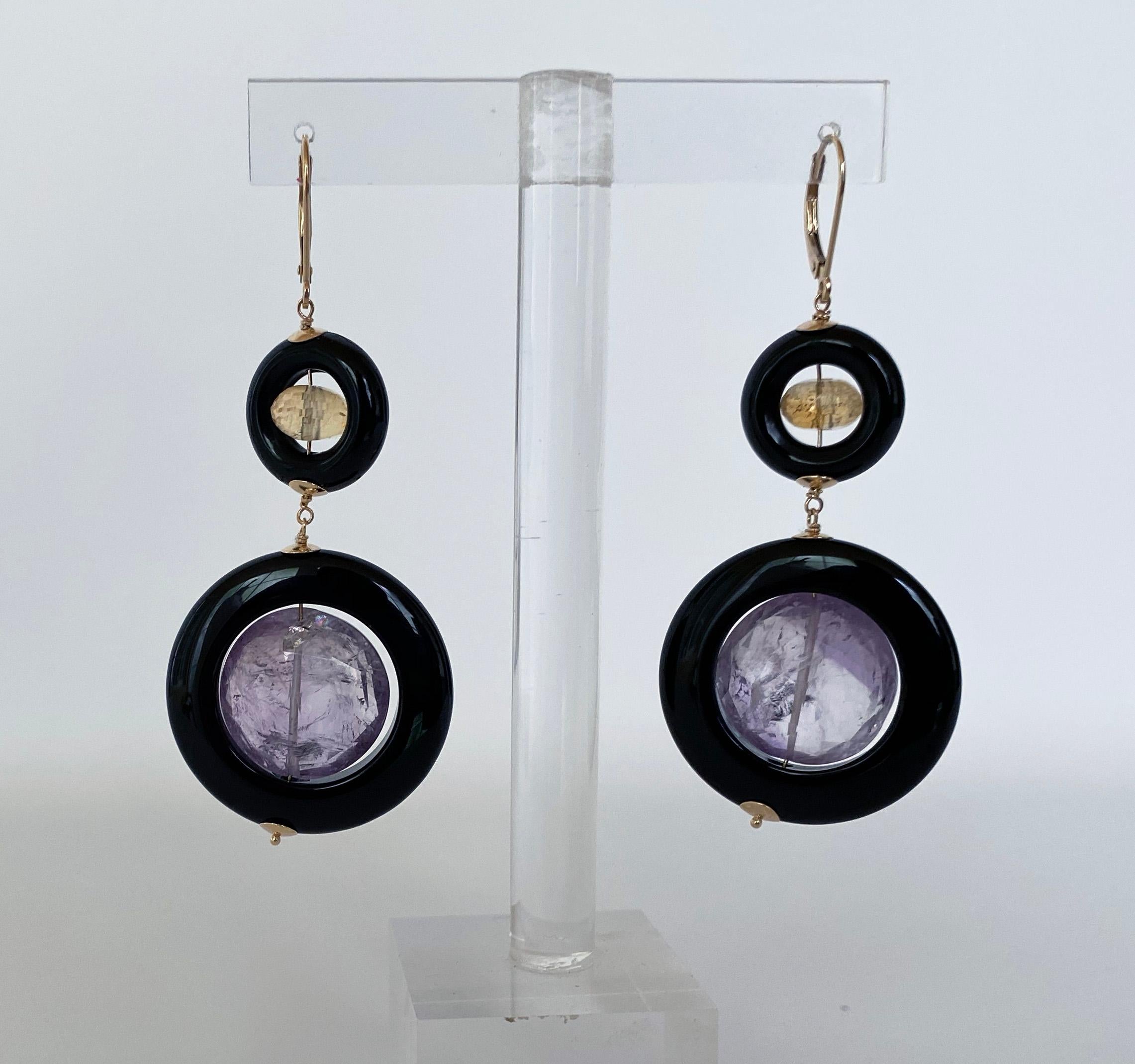 These elegant dangle earrings display beautifully bright and complimentary gemstones. This piece features faceted Cirtrine and large Amethyst beads freely moving within Black Onyx rings. The Black Onyx is perfectly contrasted by 14K Yellow Gold