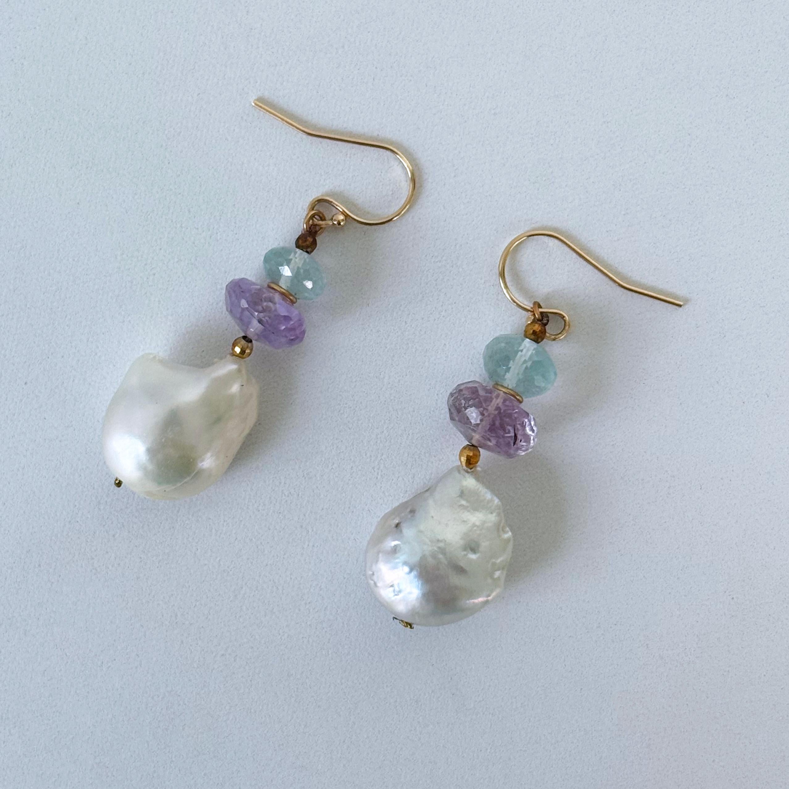 Le perle rotonde di acquamarina e ametista sono punteggiate da perline in oro 14k e si trovano in cima a una grande ed eccentrica perla barocca. Assicurata con un gancio in oro giallo 14k, la perla penzola e si muove liberamente a ogni passo.