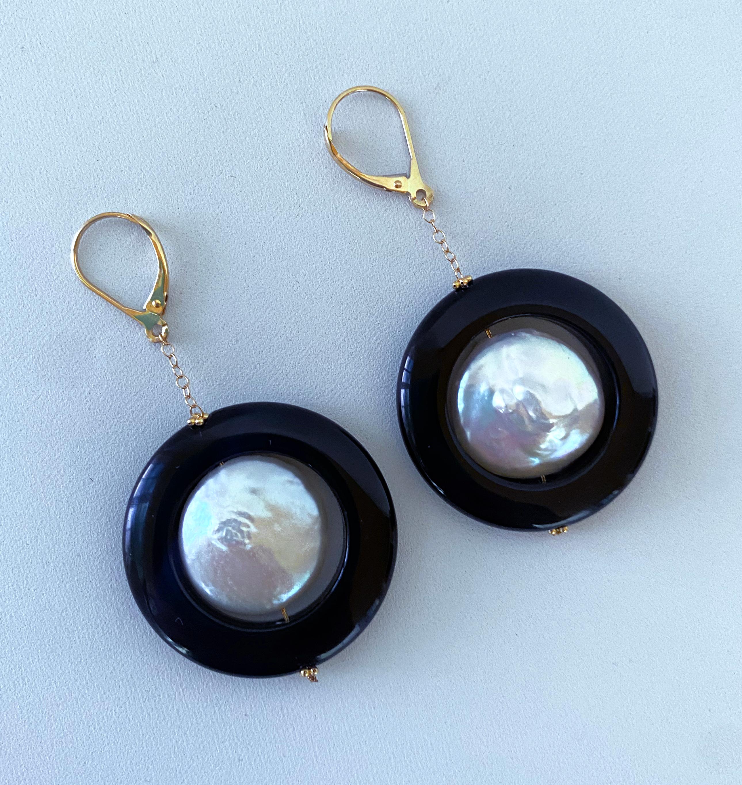 Gorgeous pair of Earrings by Marina J. This pair is made of two Baroque Pearls, displaying a beautiful iridescent luster that softly flashes hues of pinks and blues. The Pearls are suspended within a black Onyx ring which hangs off a solid 14k