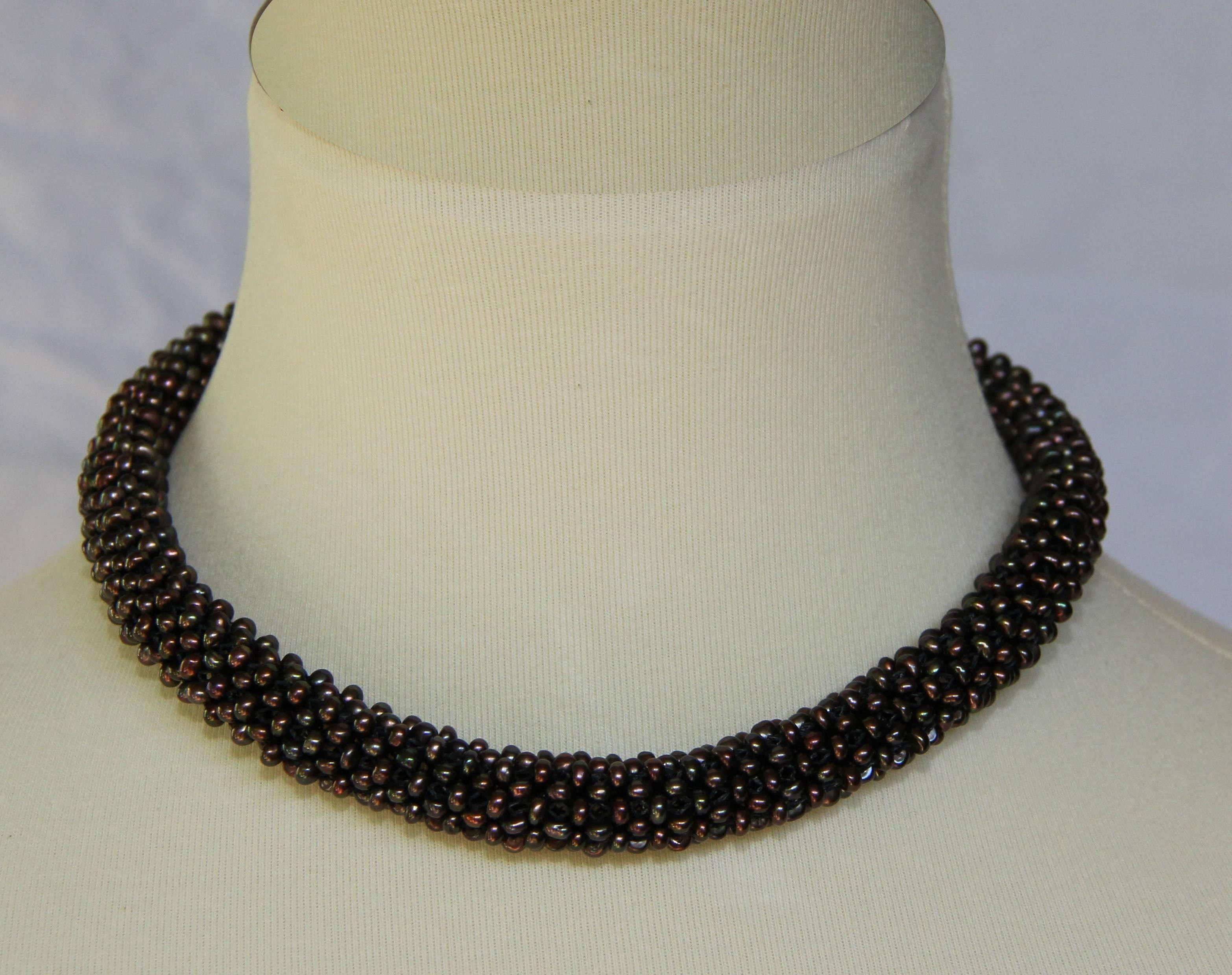 Black color pearl beads are woven together to create a dimensional rope like necklace. They form a thick tubular rope of approximately 1/3 of an inch in diameter. This unique, modern and one-of-a-kind necklace can be worn day or night, casual or