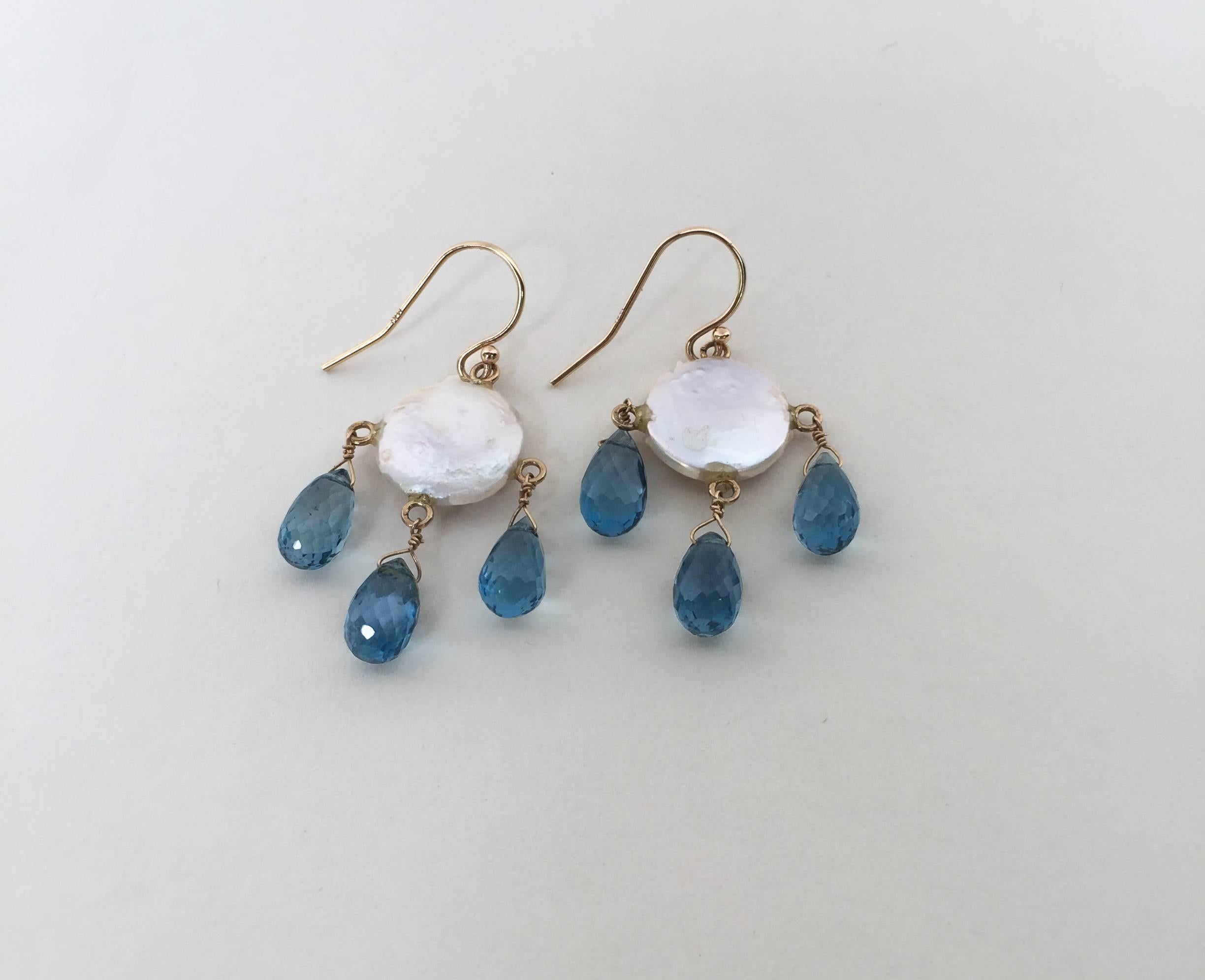 These whimsical earrings are highlighted by the iridescent colors of the coin pearl and London blue topaz drop beads. Running through the design is 14k yellow gold wiring completed with a hook of the same material. They are 1.5 inches long dangling