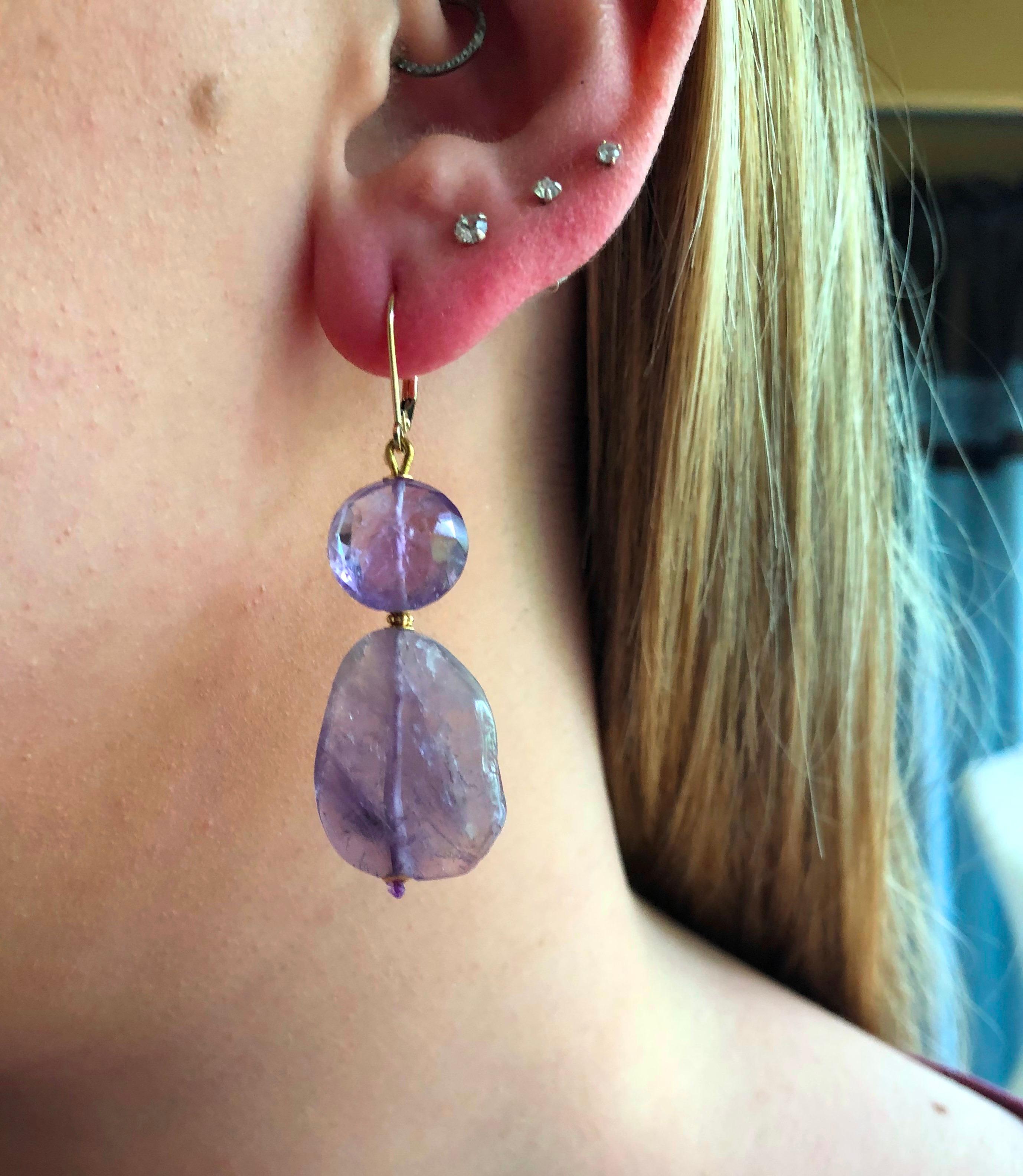 These fabulous double asymmetrical amethyst bead gemstone earrings with 14 k yellow gold wiring and lever-back have a graceful look to them. At 1.75 inches long the earring classically frames the face. The contrast of the amethyst bead with the