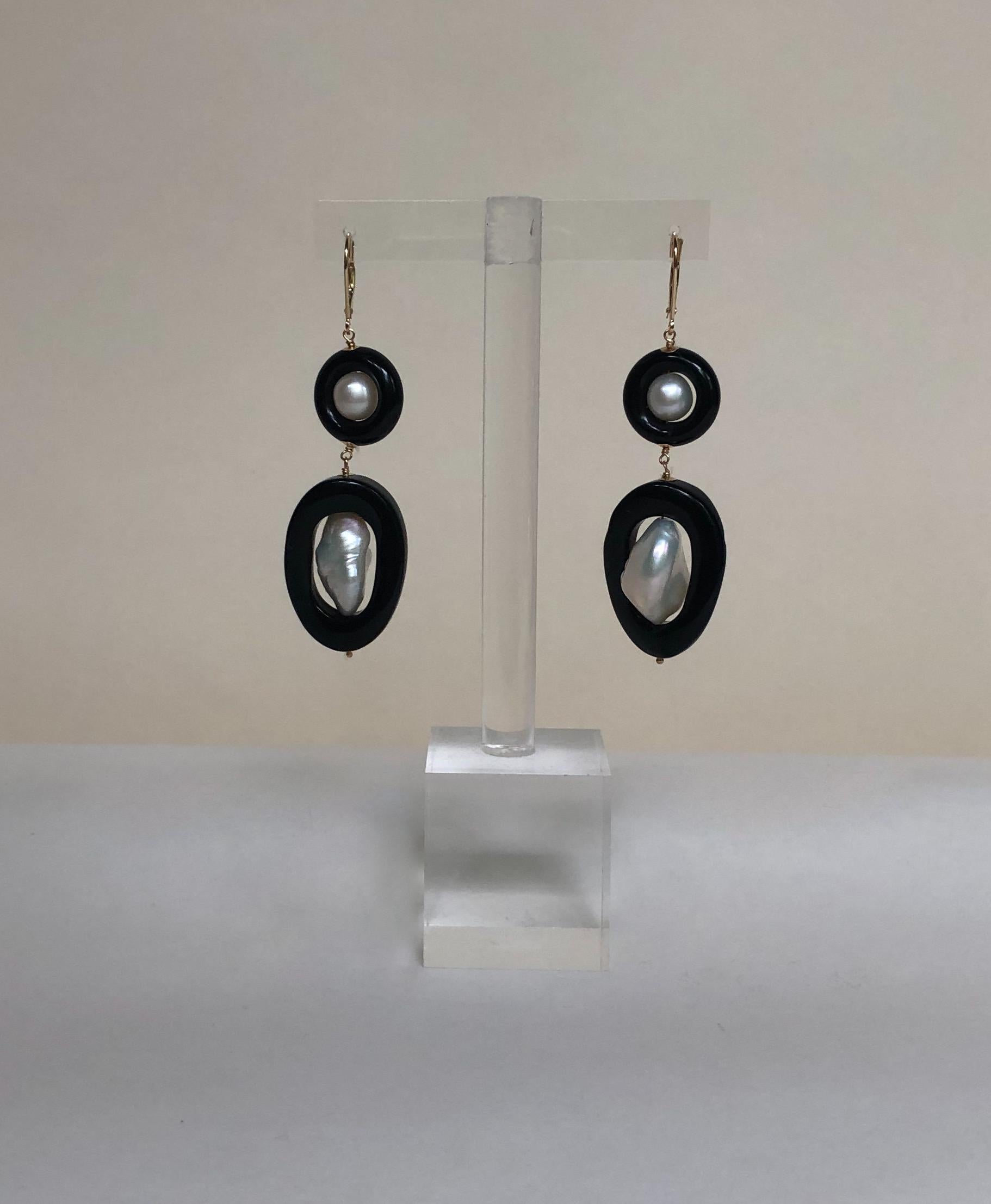 These beautiful, unique earrings are made from black onyx and pearls. The wiring and leverback are made from 14k yellow gold. The onyx ring contrasts with the glowing white pearl beautifully, which is sure to make a statement in any look. The
