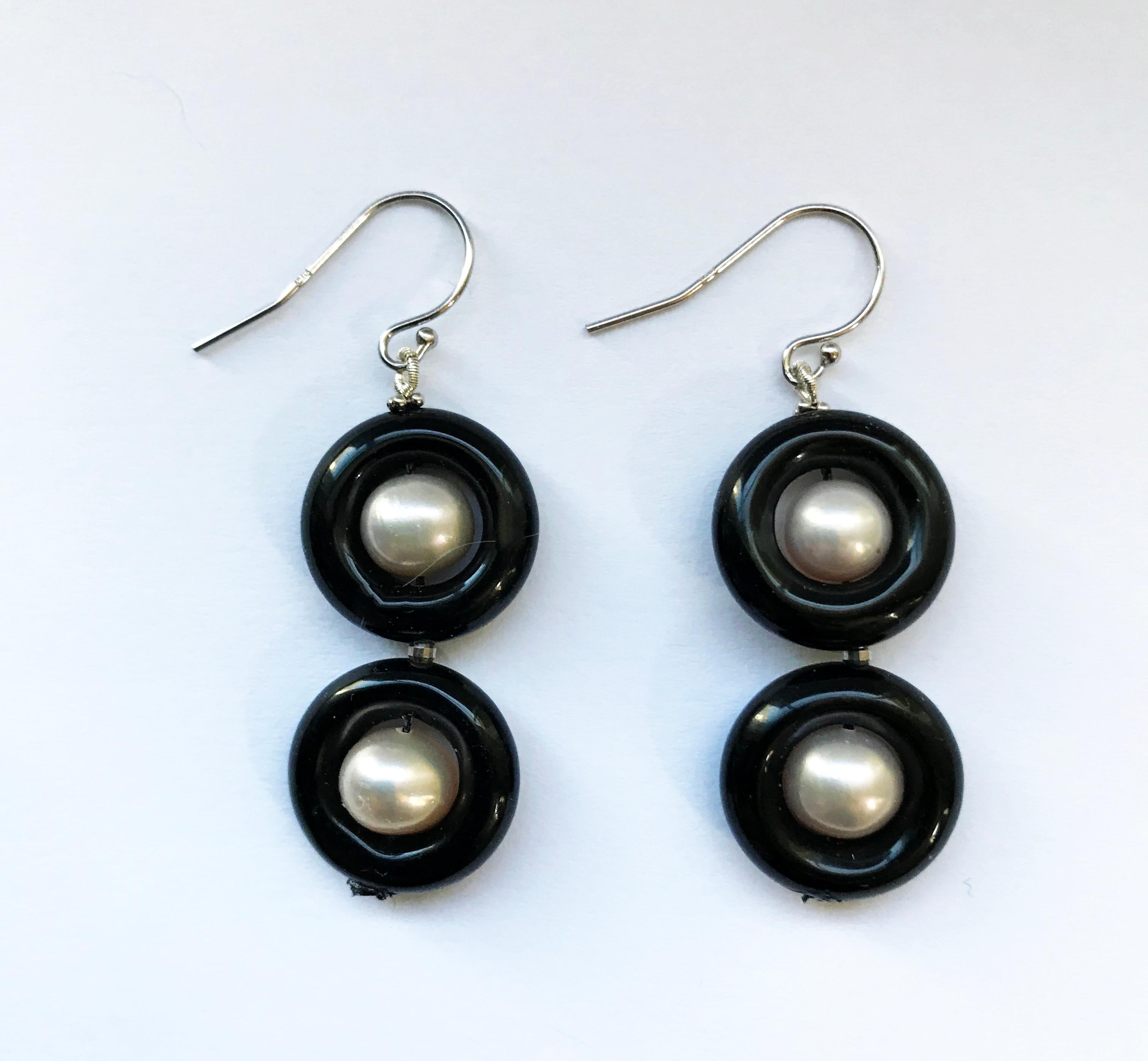 These classic double black onyx and pearl earrings with 14 k white gold hook and wiring are elegant and bold. The onyx rings contrast with the glowing white pearls beautifully making, what could have been simple earrings dramatic and eye-catching.