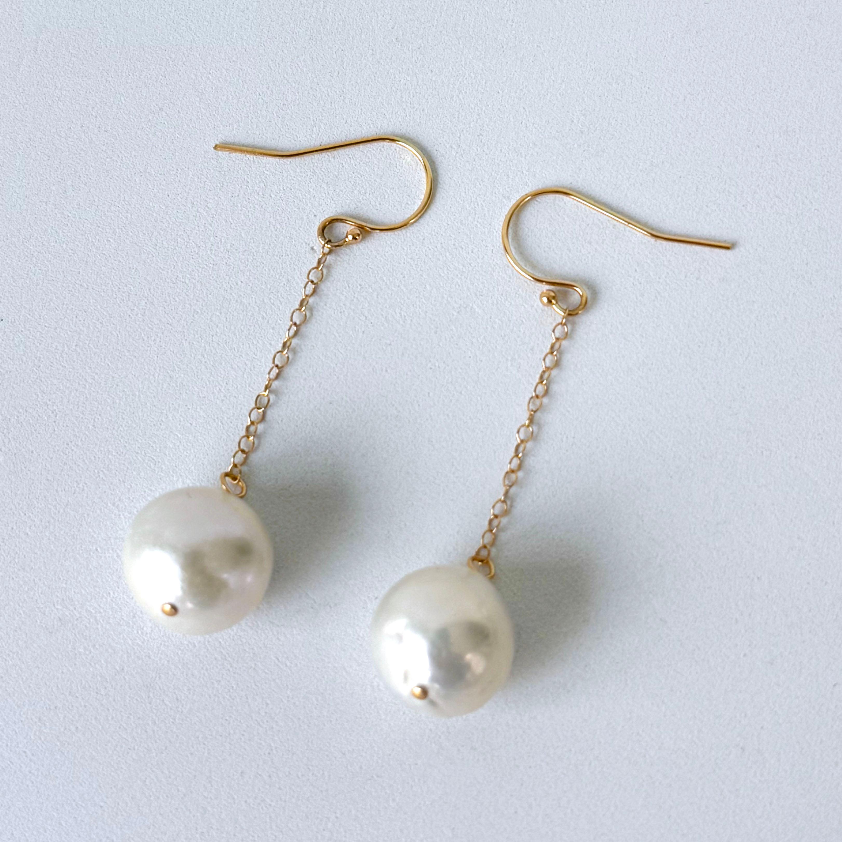 Simple and elegant pair of Earrings by Marina J. 
This pair of made of two smooth round white Pearls displaying a soft iridescent luster. The Pearls are suspended on Solid 14k Yellow Gold chain from high shine Solid 14k Yellow Gold Hooks. Measuring